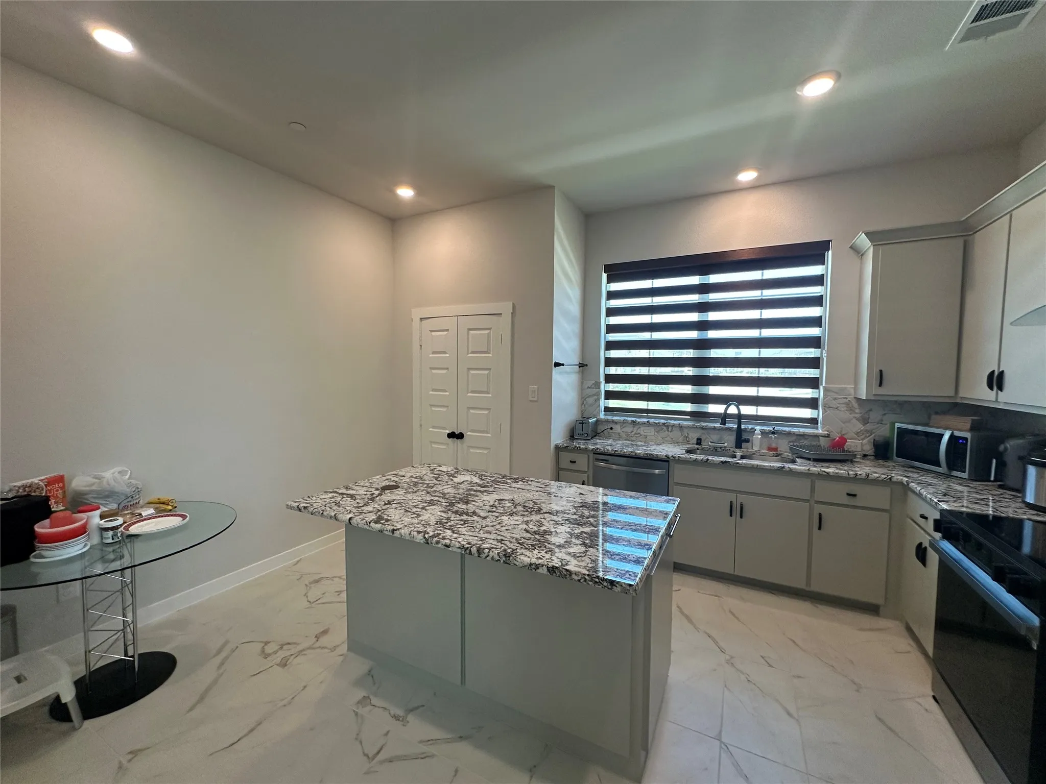Kitchen featuring an island with stone countertop, stainless steel dishwasher, undermount sink, and recessed lighting