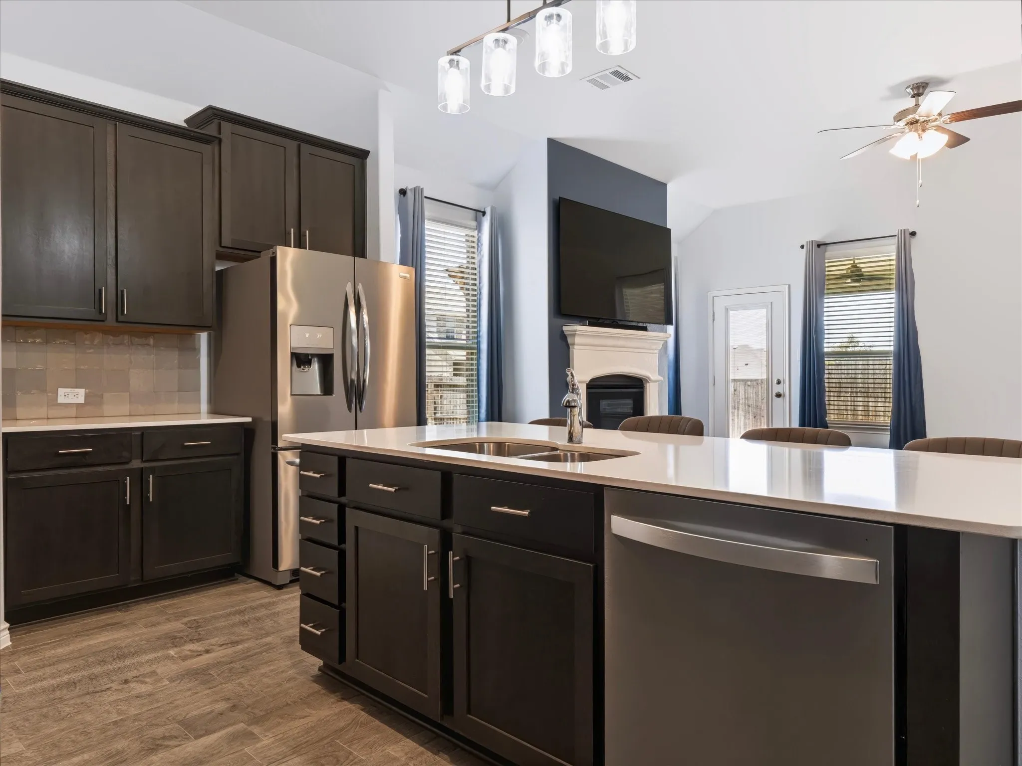 Dark wood-finish cabinetry, stainless steel appliances, light-toned countertops, and wood-look flooring