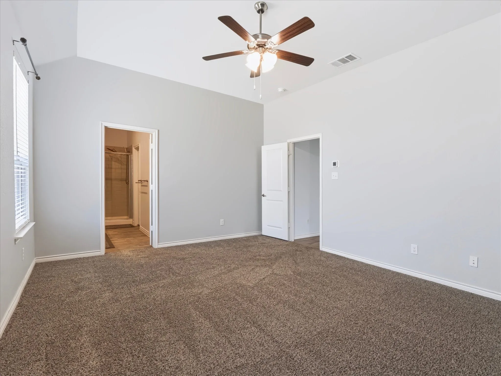 Vaulted ceiling with a ceiling fan, carpeted flooring, and a window with blinds