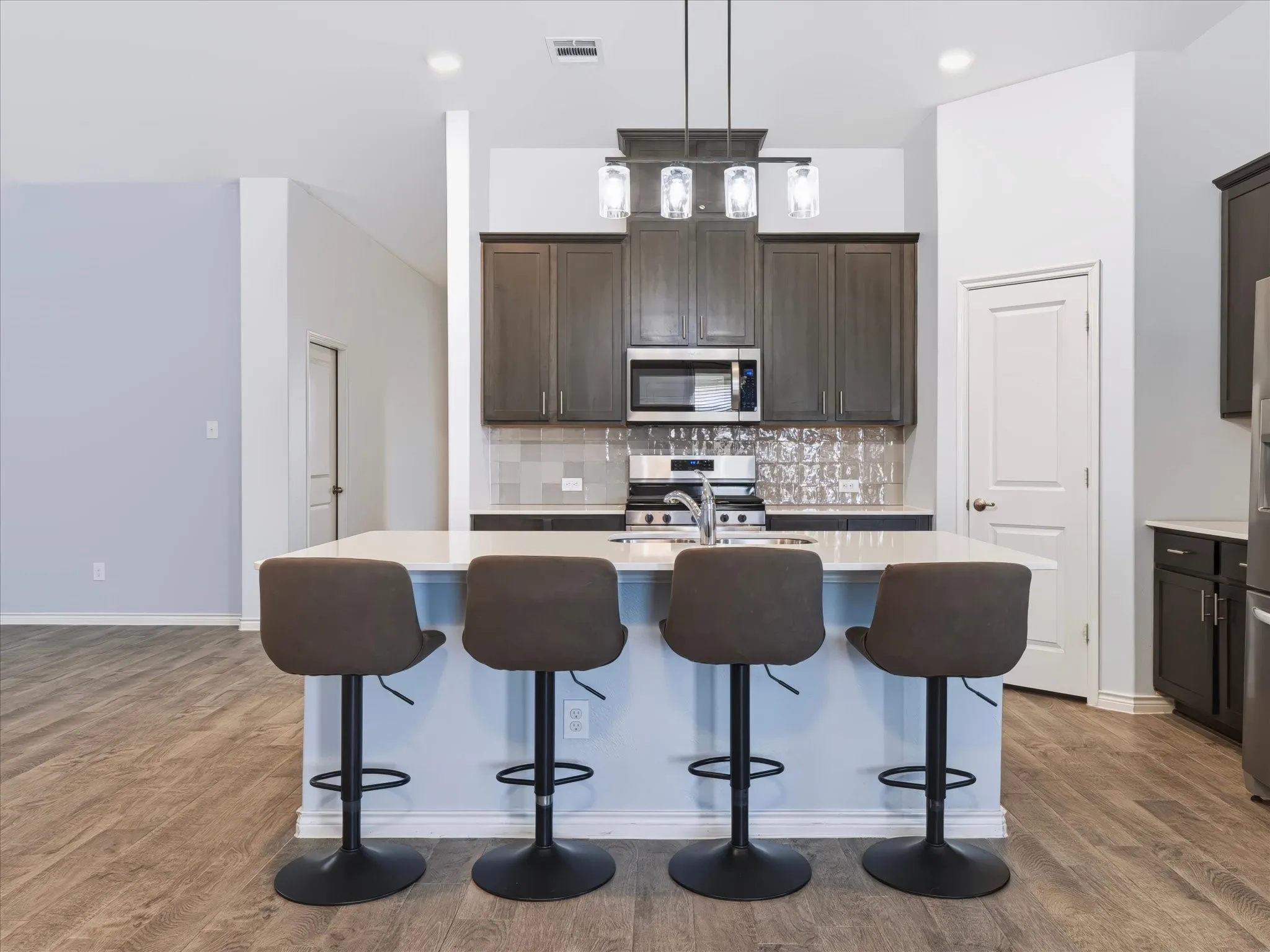Kitchen island featuring a white countertop, under-mount sink, and pendant lighting