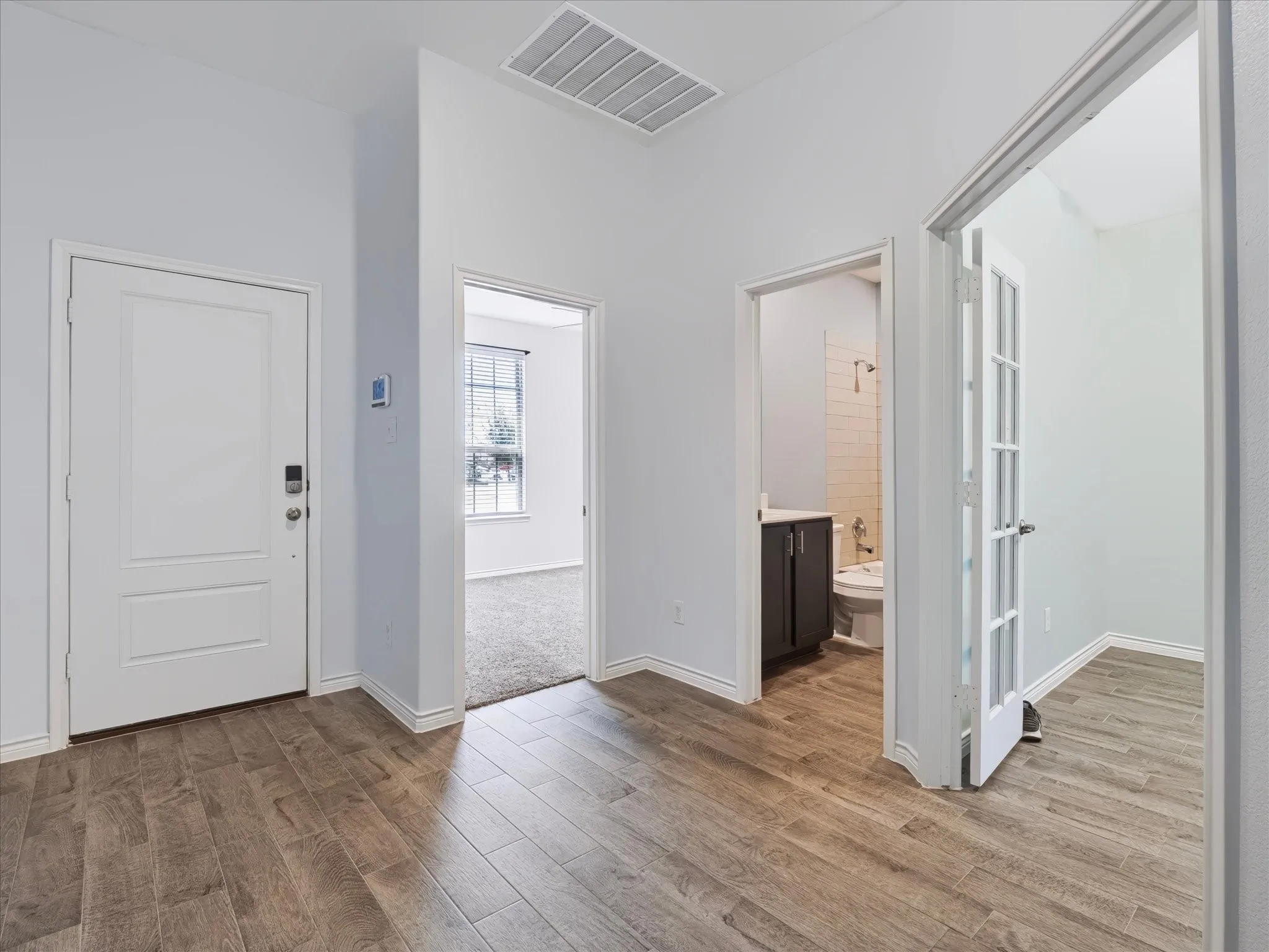 Wood-finish flooring, white paneled doors, french doors, and high ceilings