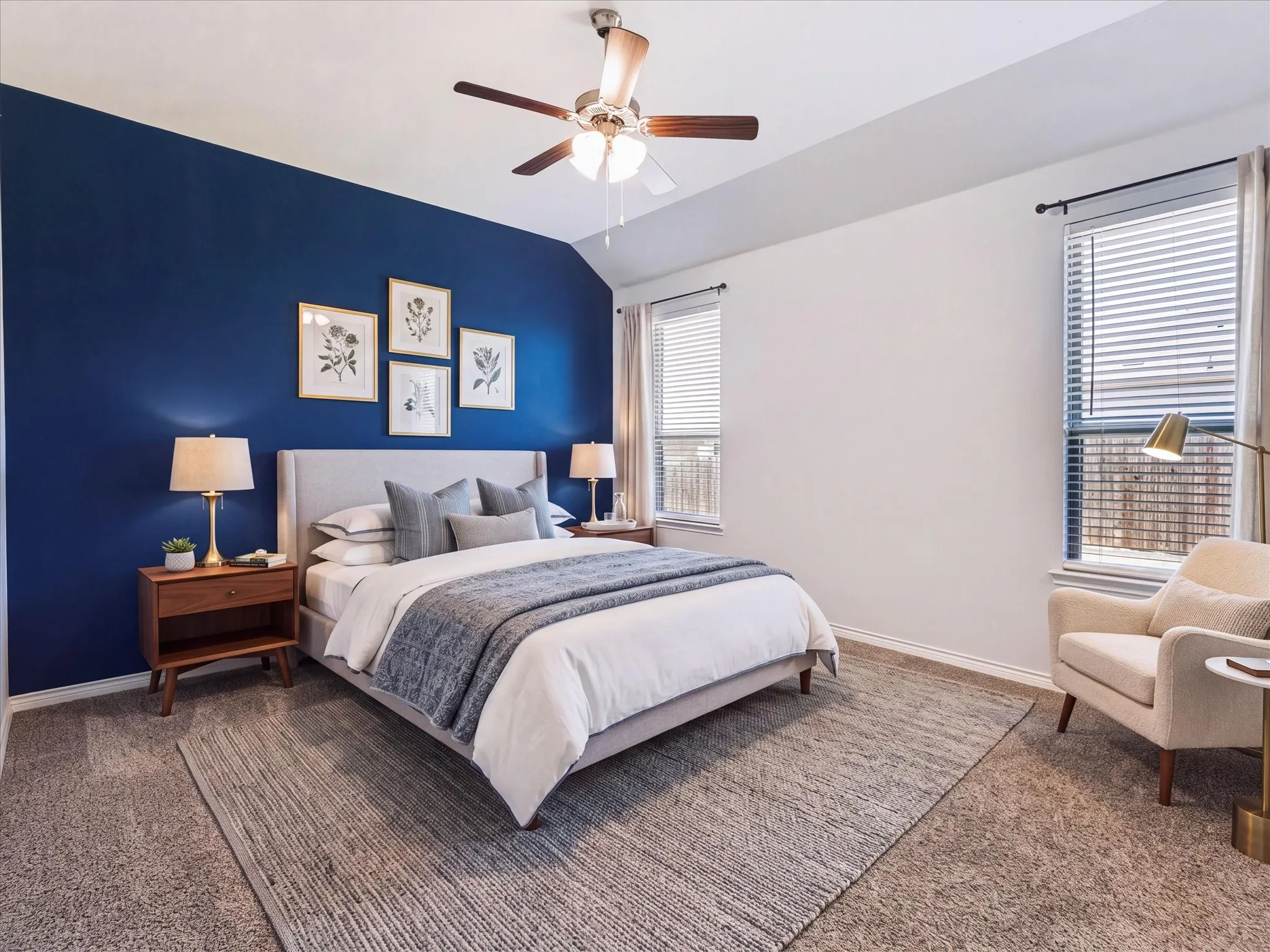 Vaulted ceiling with a ceiling fan, carpet flooring, dual windows with blinds, and a bold accent wall