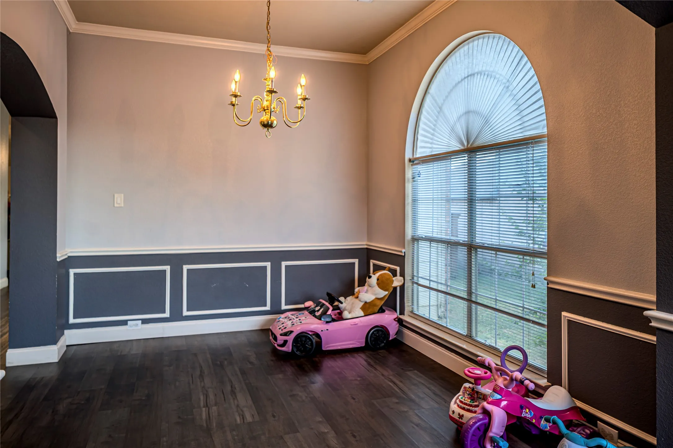 Arch top window with blinds, dark wood-finish flooring, and crown molding