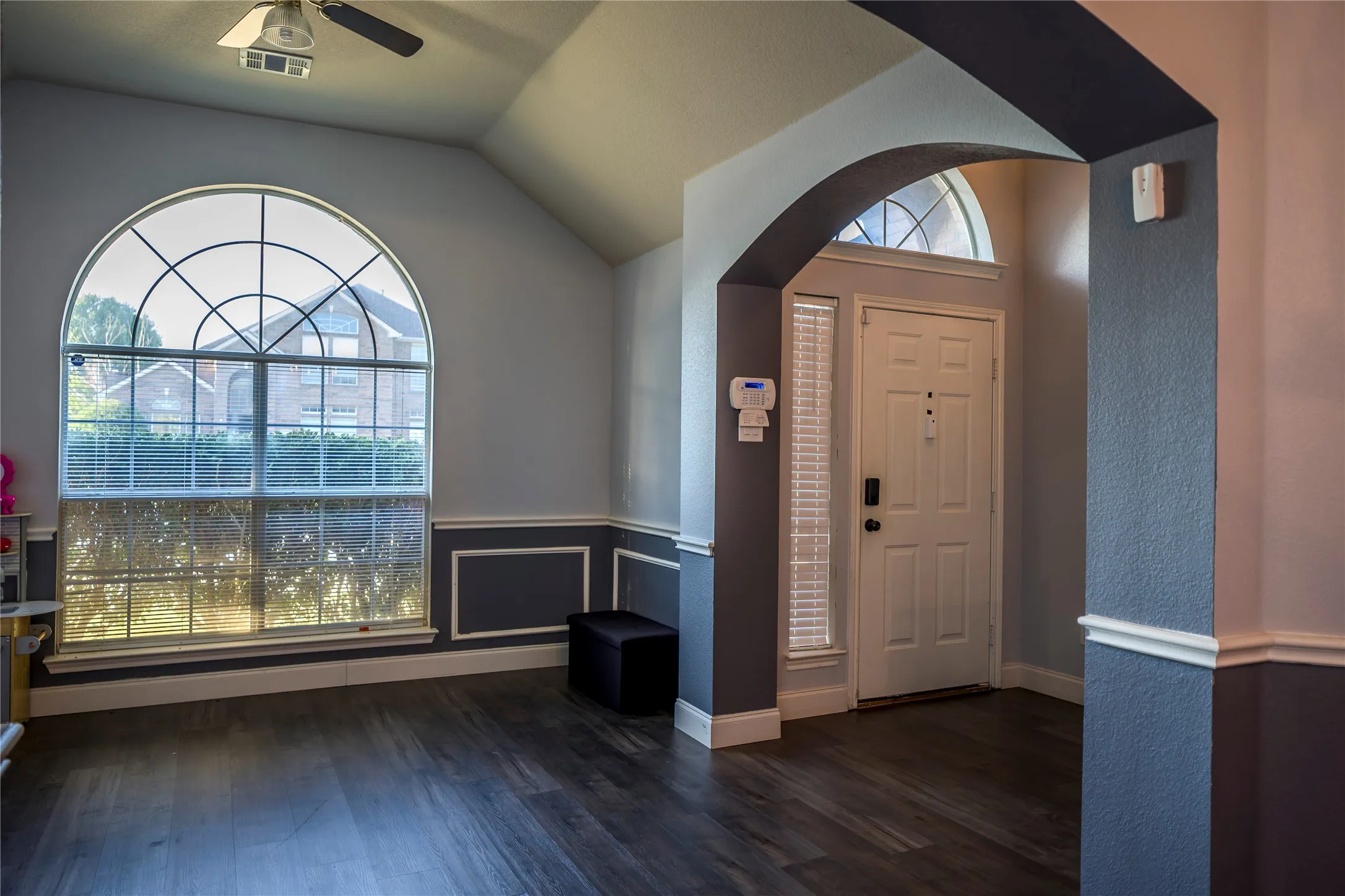 Arched entryway with a transom window, wood-finish flooring, and decorative wall molding
