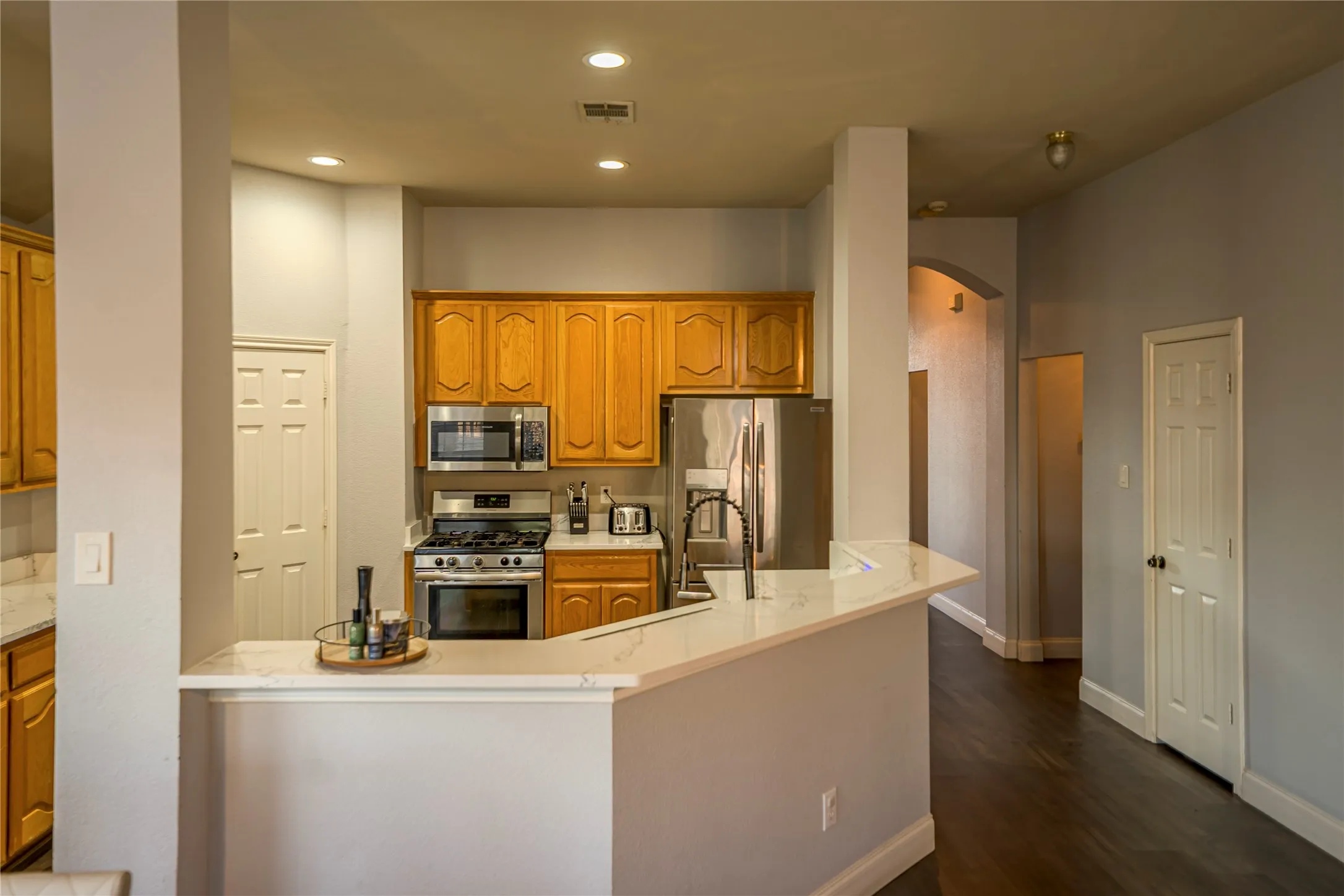 Kitchen featuring wood cabinetry, stainless steel appliances, and a breakfast bar with a light-toned countertop