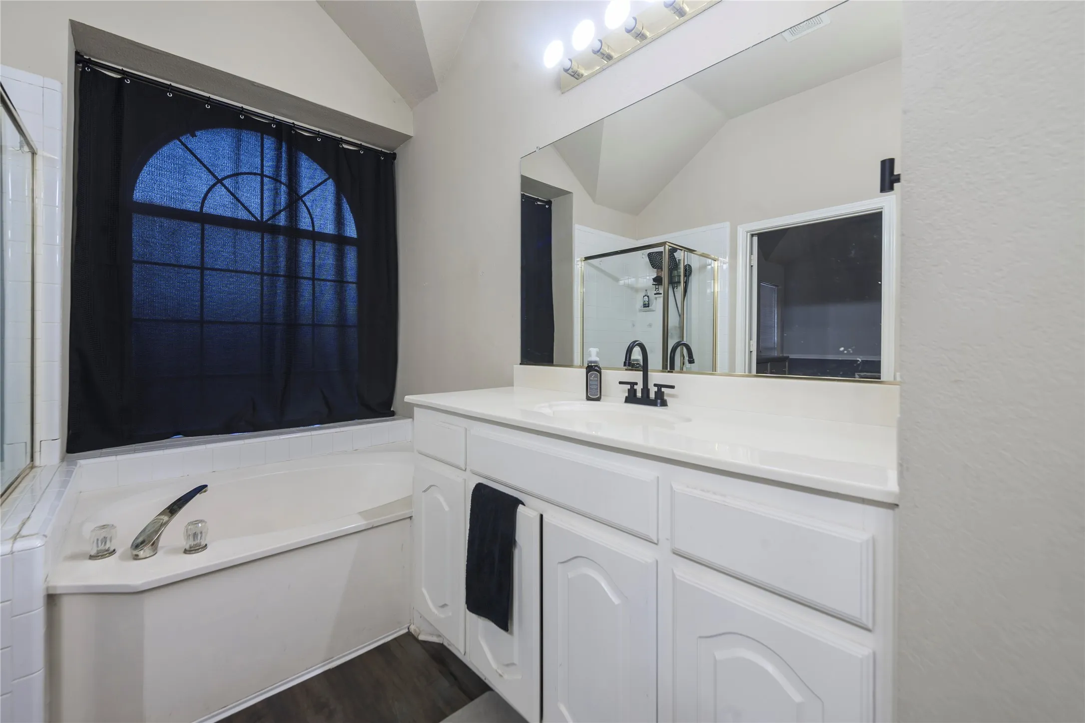 White vanity with a single basin sink, black-finish faucet, and a large mirror