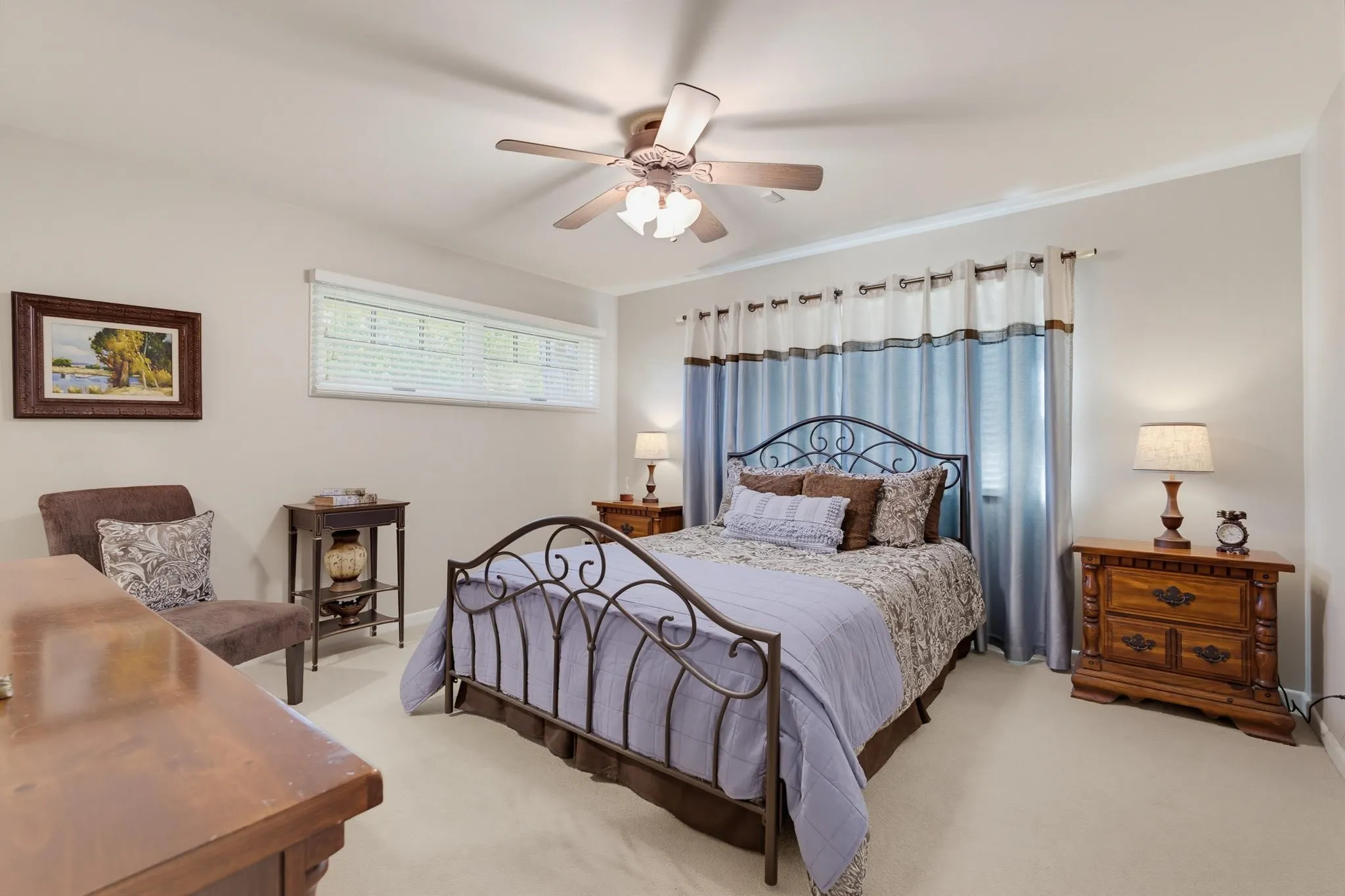 Ceiling fan with integrated lighting, a horizontal window with blinds, and light-toned carpeting