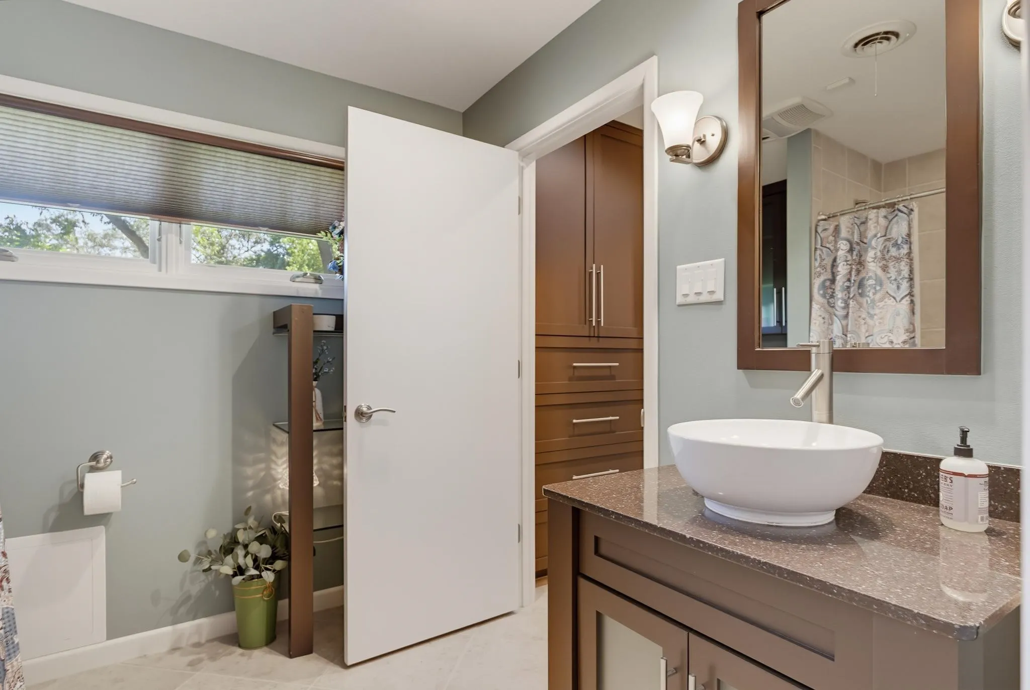 Vanity with vessel sink, wall-mounted faucet, and dark-toned cabinetry