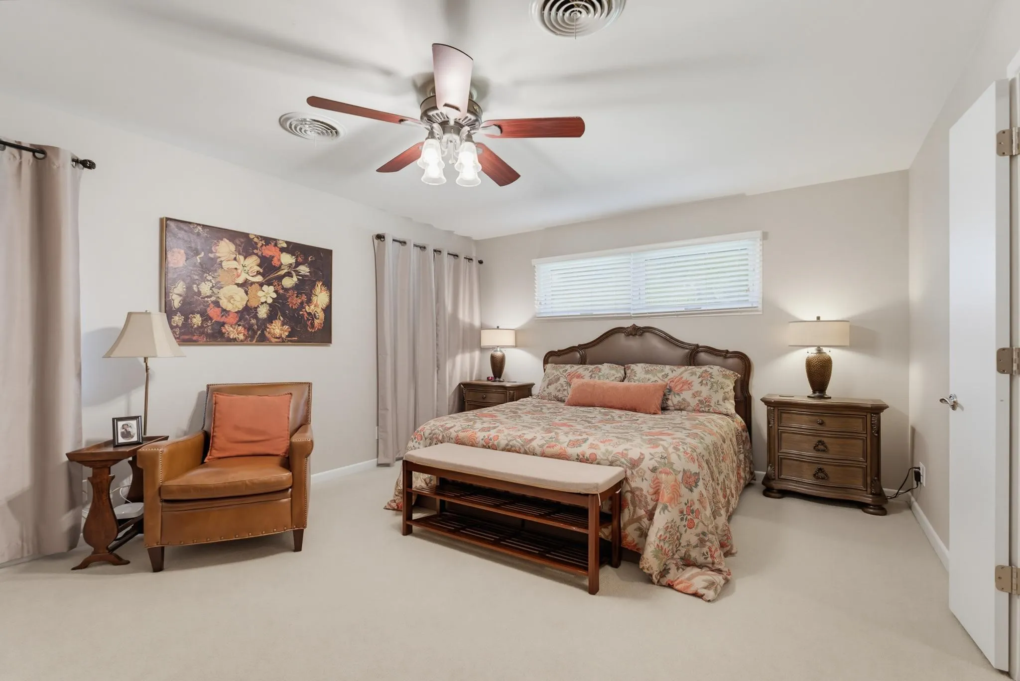 Neutral wall color, ceiling fan with integrated lighting, window with blinds, light-toned carpeting, and a white door