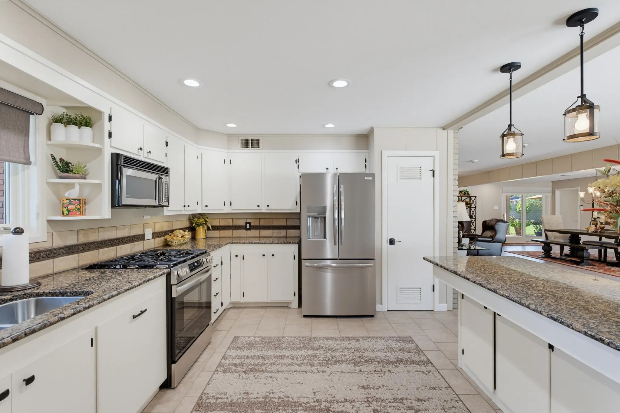 Kitchen featuring white cabinetry, stainless steel appliances, granite countertops, tile flooring, and recessed lighting