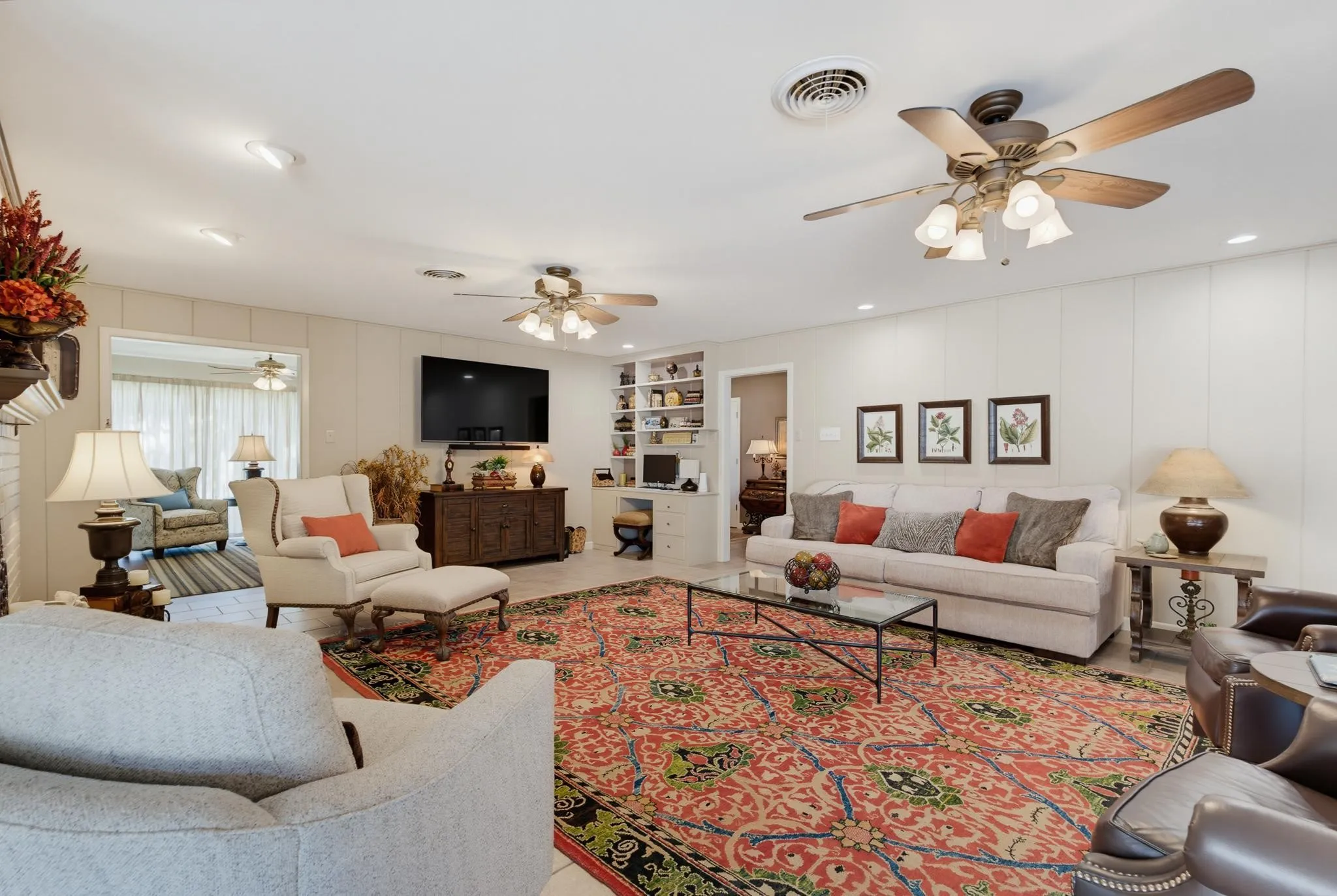 Recessed lighting, wood-paneled walls, built-in shelving, two ceiling fans, and tiled flooring