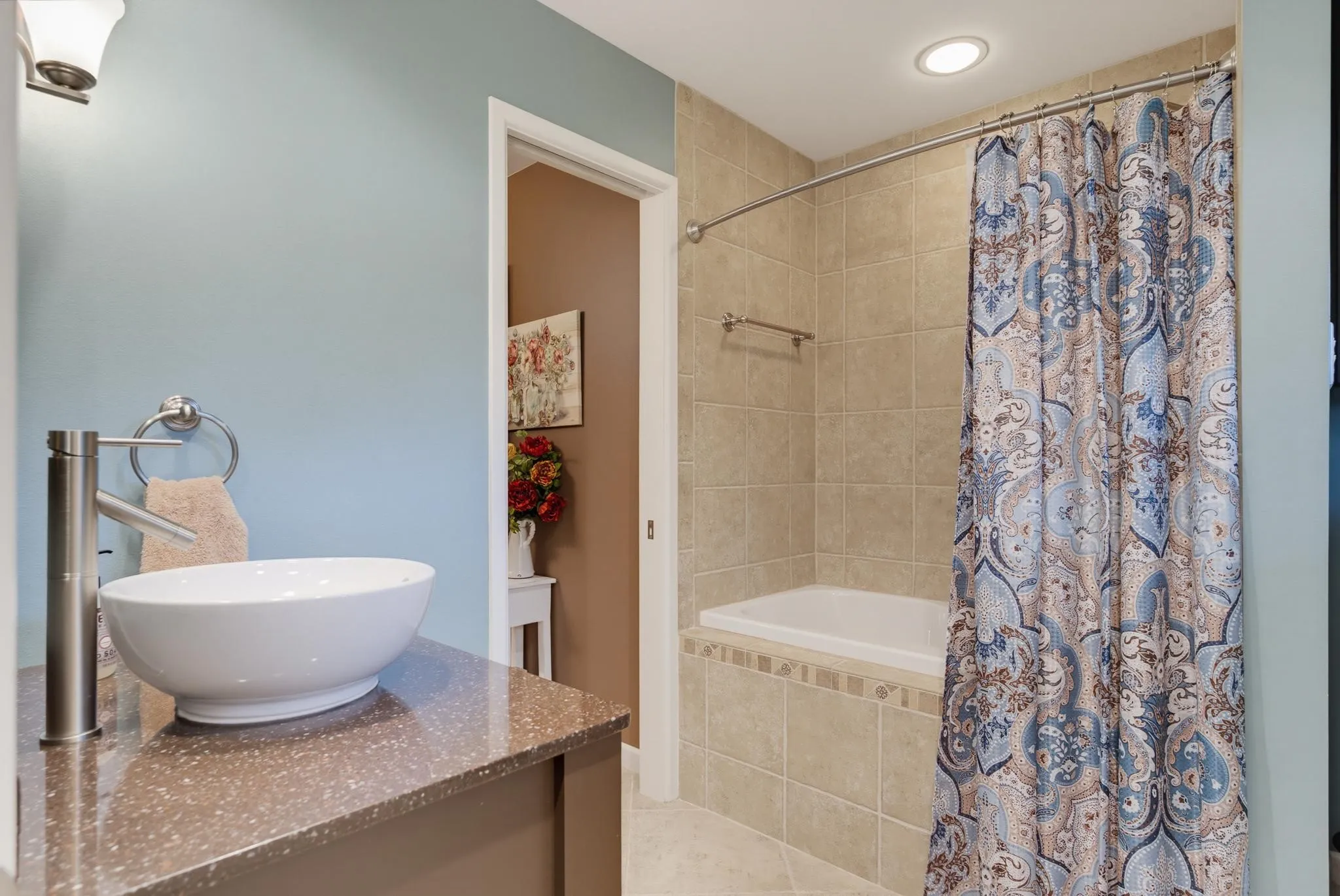 Bathroom featuring a vessel sink, single-handle faucet, stone-look countertop, tile-surround tub, and recessed lighting