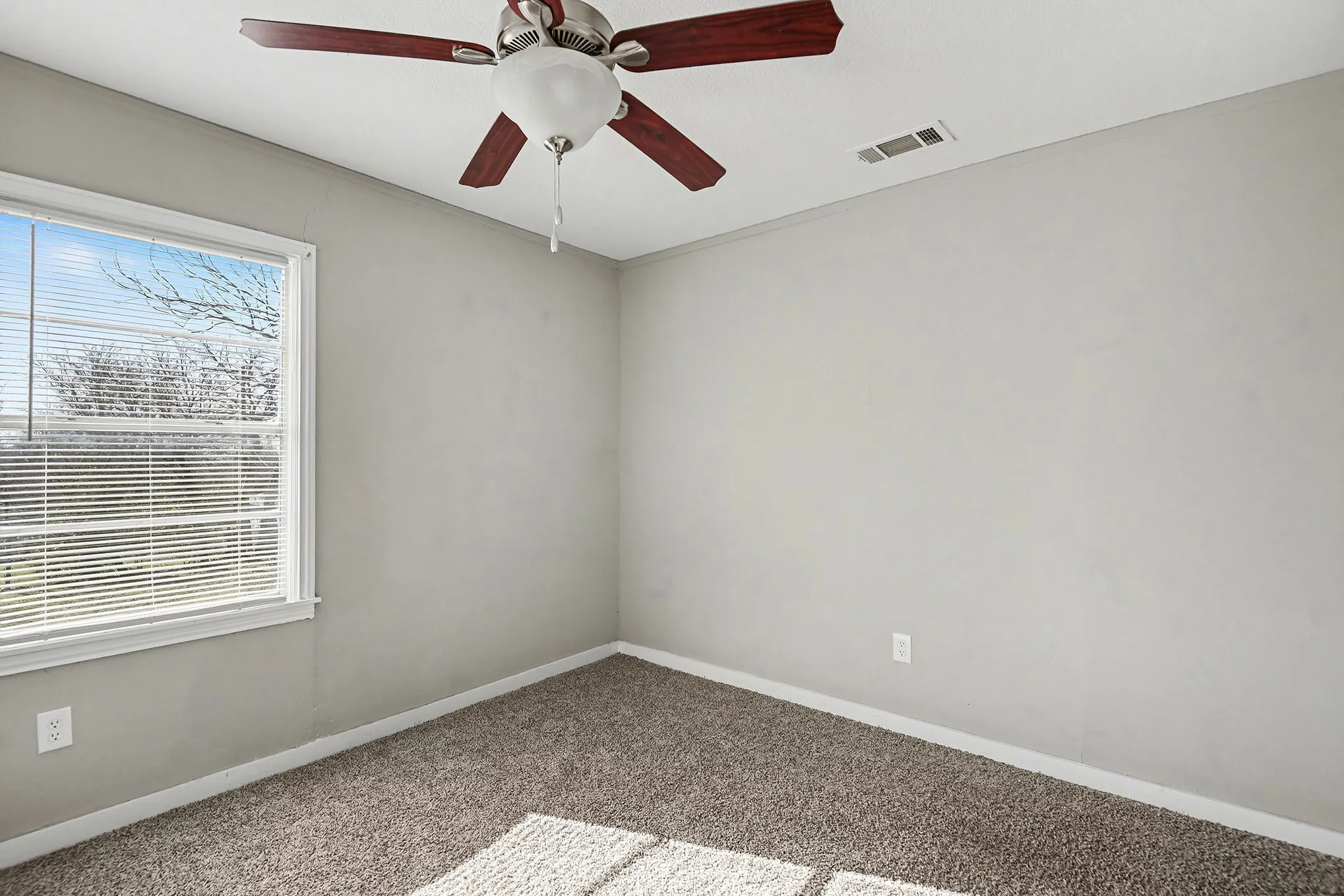 Neutral wall color, carpet flooring, window with blinds, and ceiling fan with integrated lighting