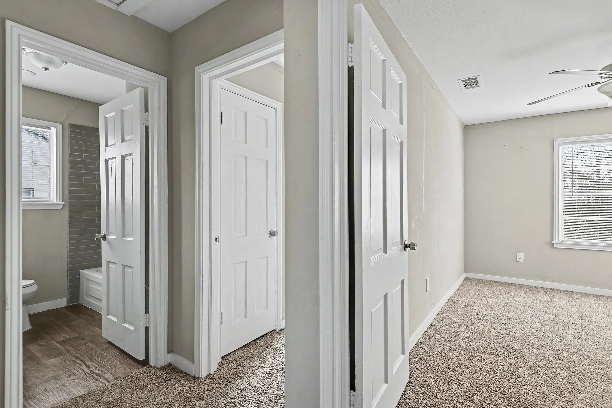 Carpeted flooring, paneled interior doors, and a window with a ceiling fan in the room