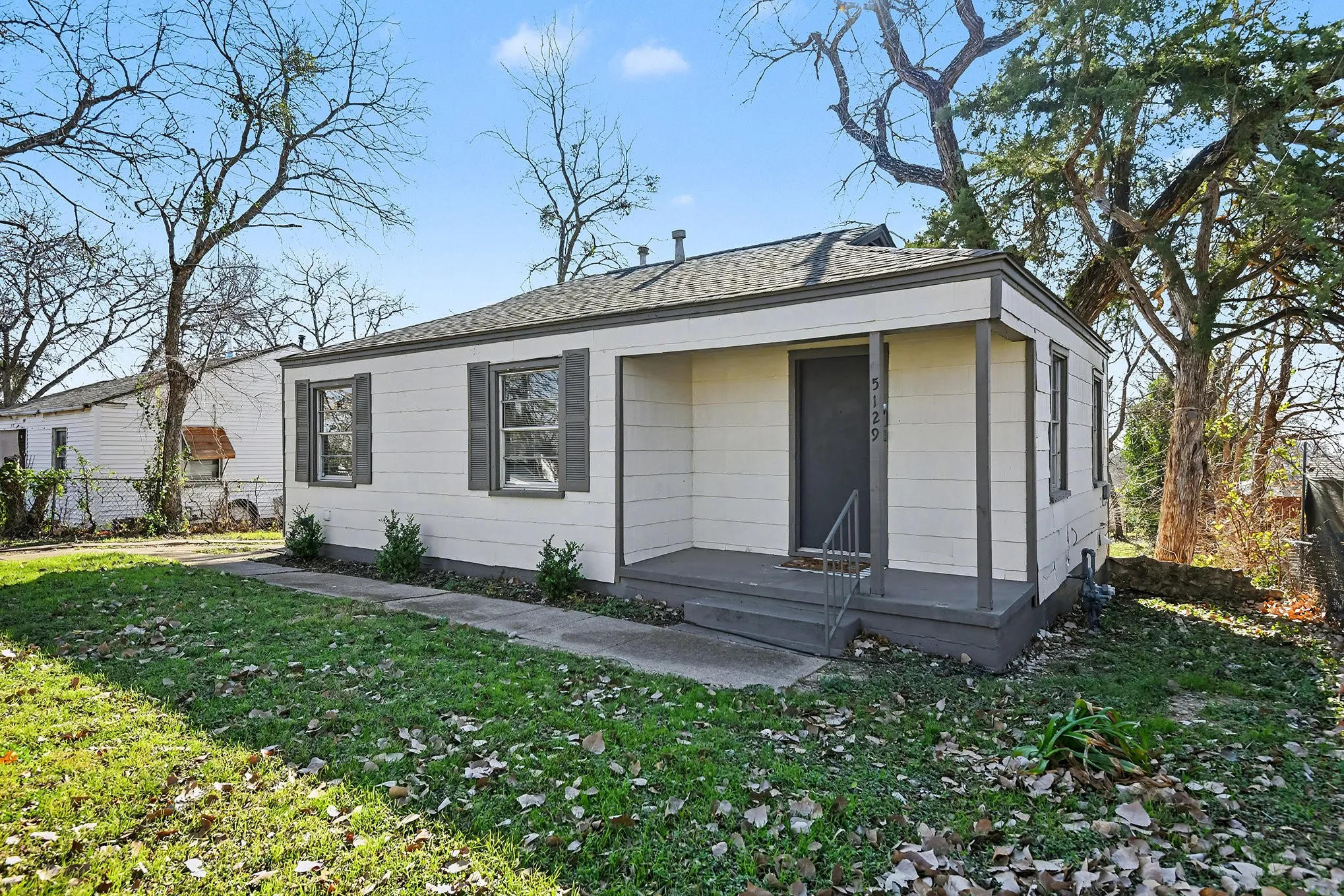 Single-story residence featuring light-colored horizontal siding and dark-colored window shutters