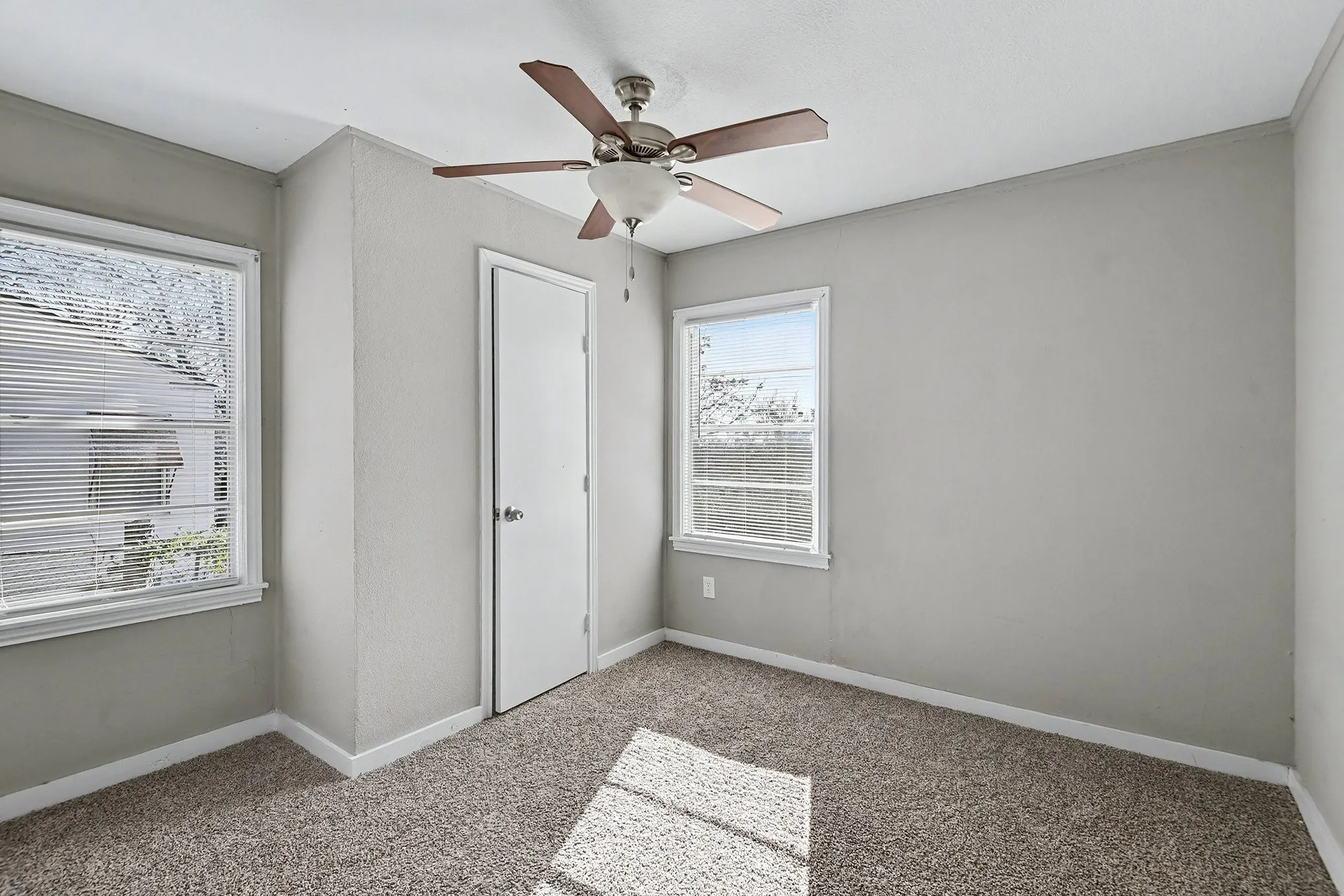 Gray painted walls, white trim, two windows, ceiling fan with integrated lighting, and carpet flooring