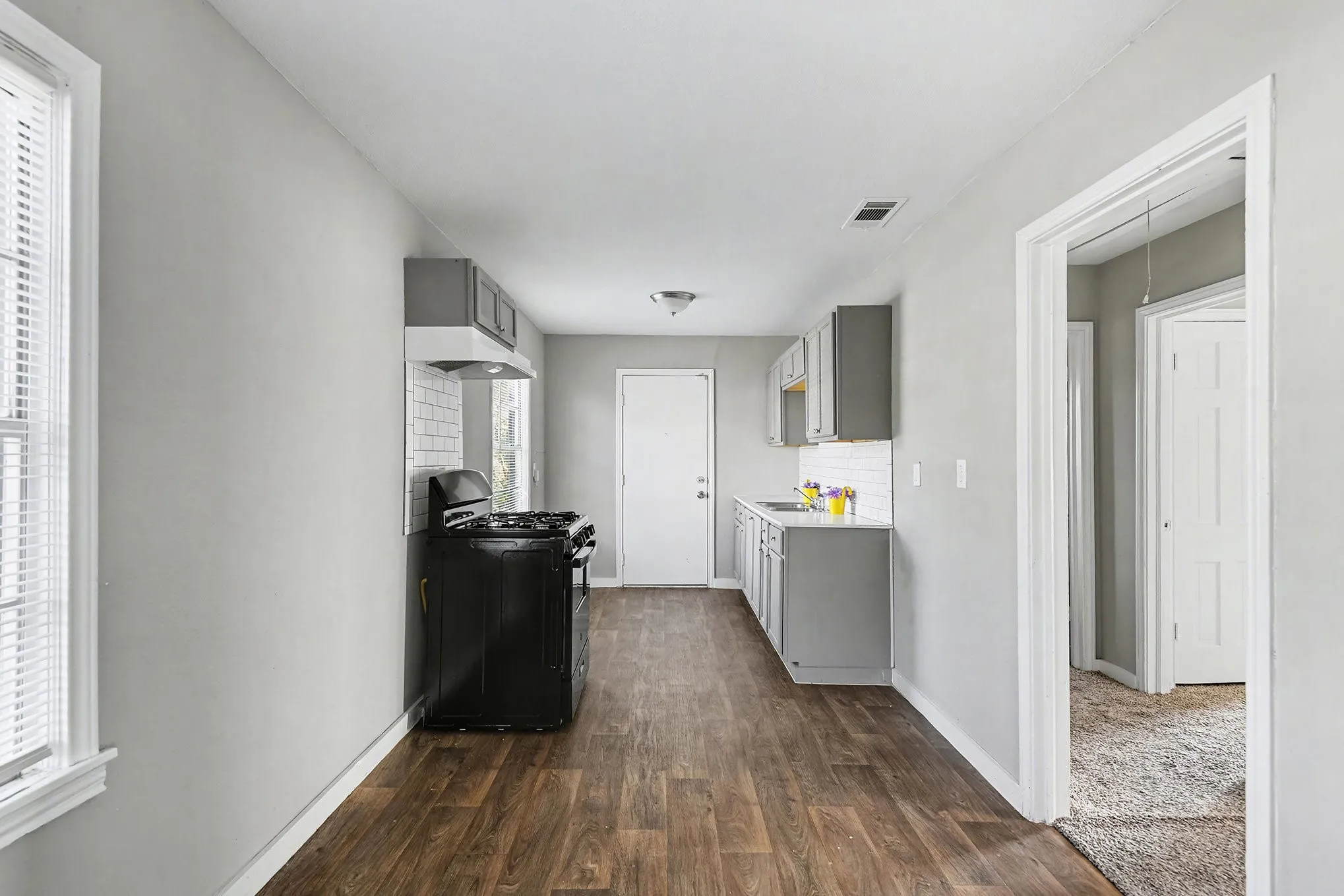 Open-concept kitchen with wood-finish flooring, gray cabinetry, white subway tile backsplash, and a white ceiling