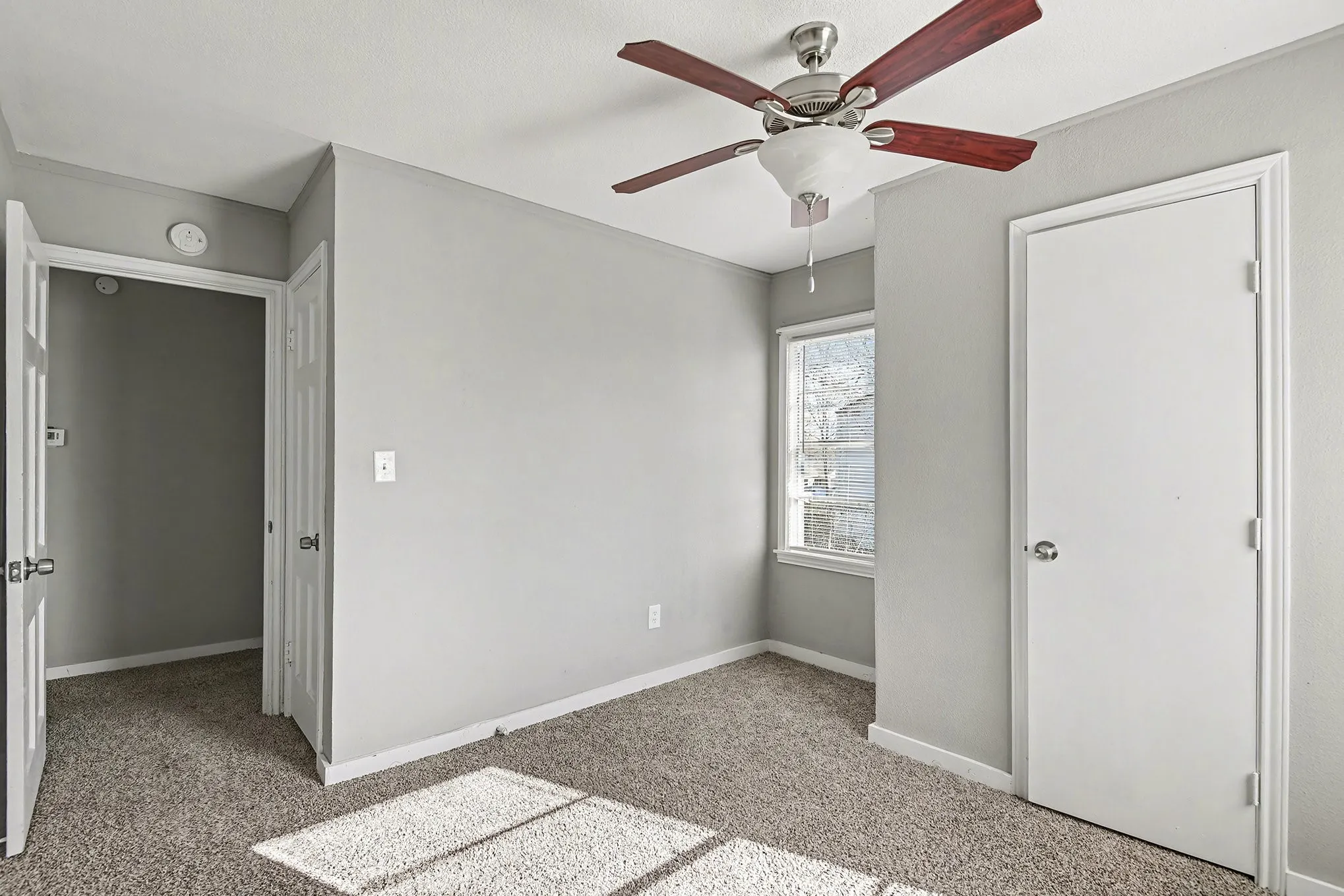 Recessed window, ceiling fan with wood-finish blades, and carpeted flooring