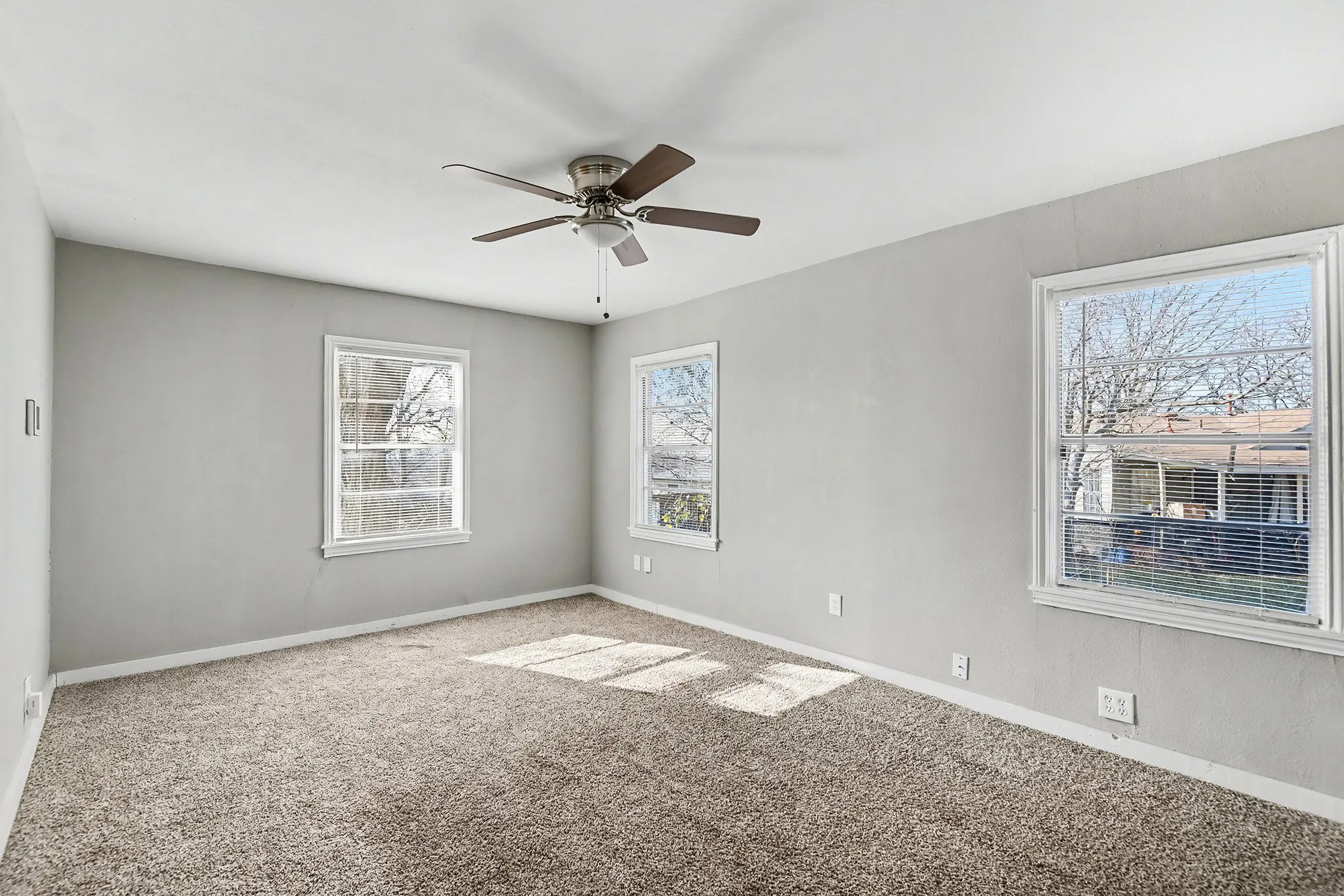 Neutral carpeting and a ceiling fan with integrated lighting