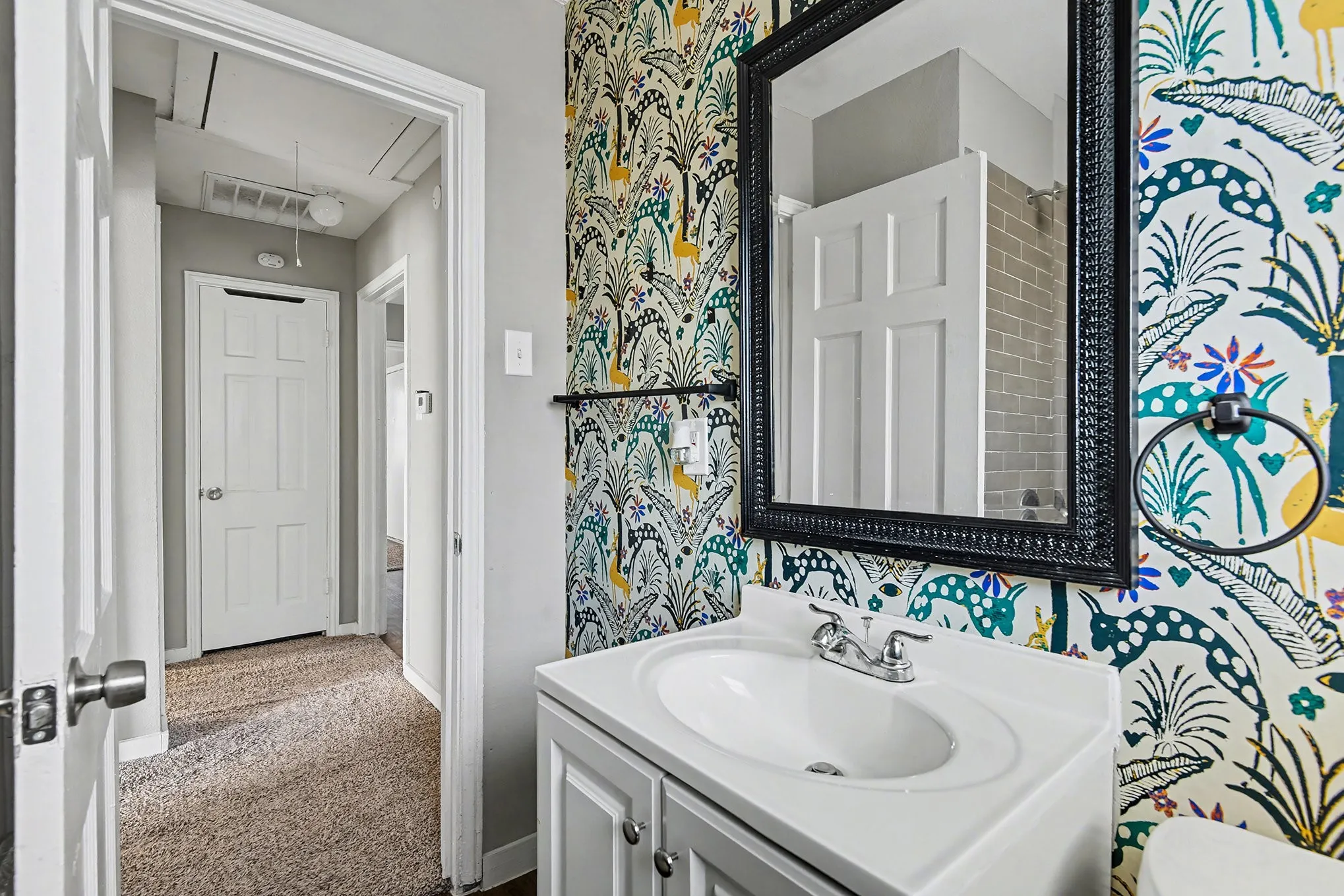 Vanity with integrated sink, patterned accent wall, framed mirror, and chrome faucet