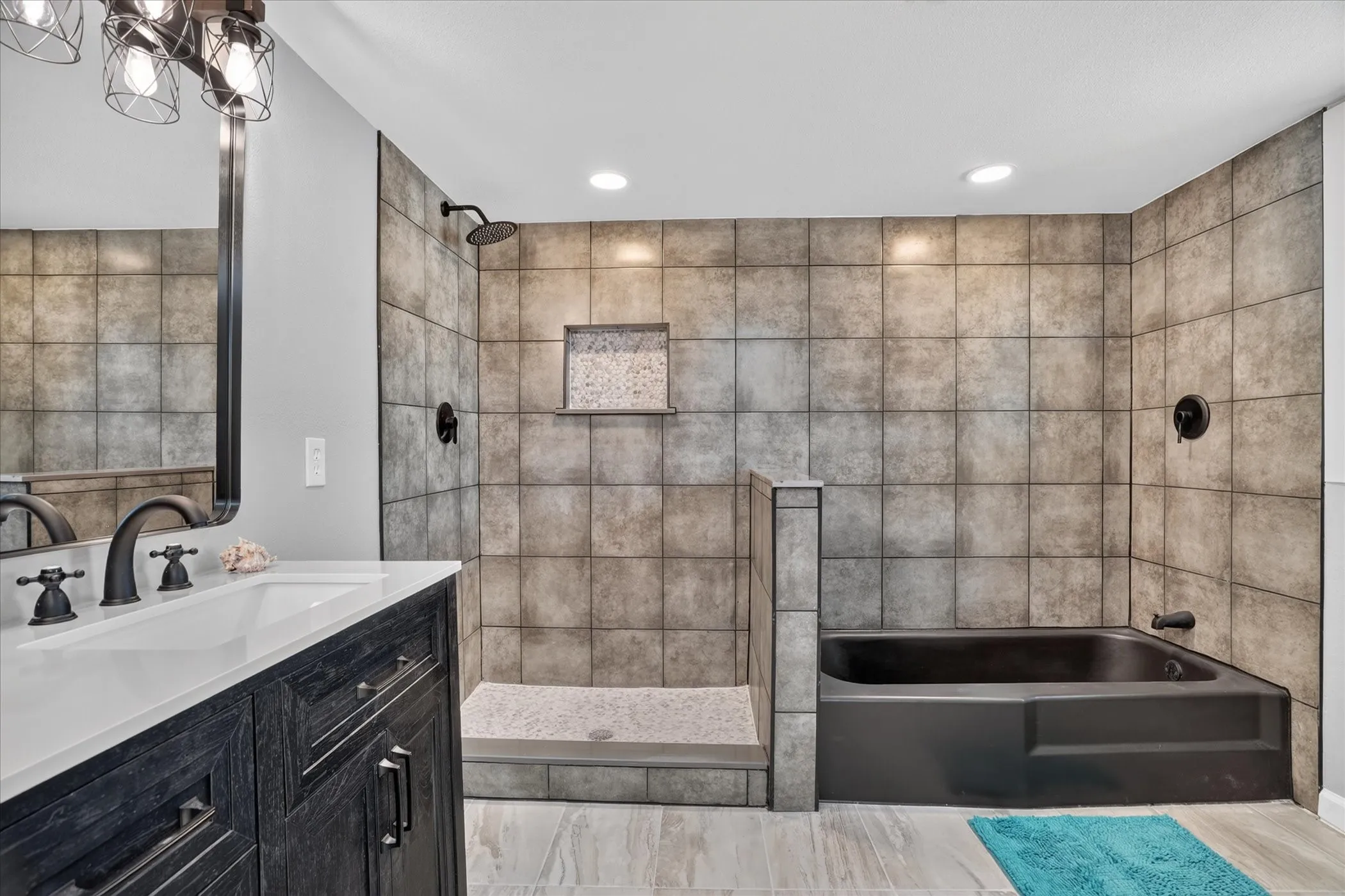 Bathroom featuring a dark wood-finish vanity with a white countertop and basin sink, matte black fixtures, a walk-in shower with a tiled surround, a built-in bathtub, and recessed lighting
