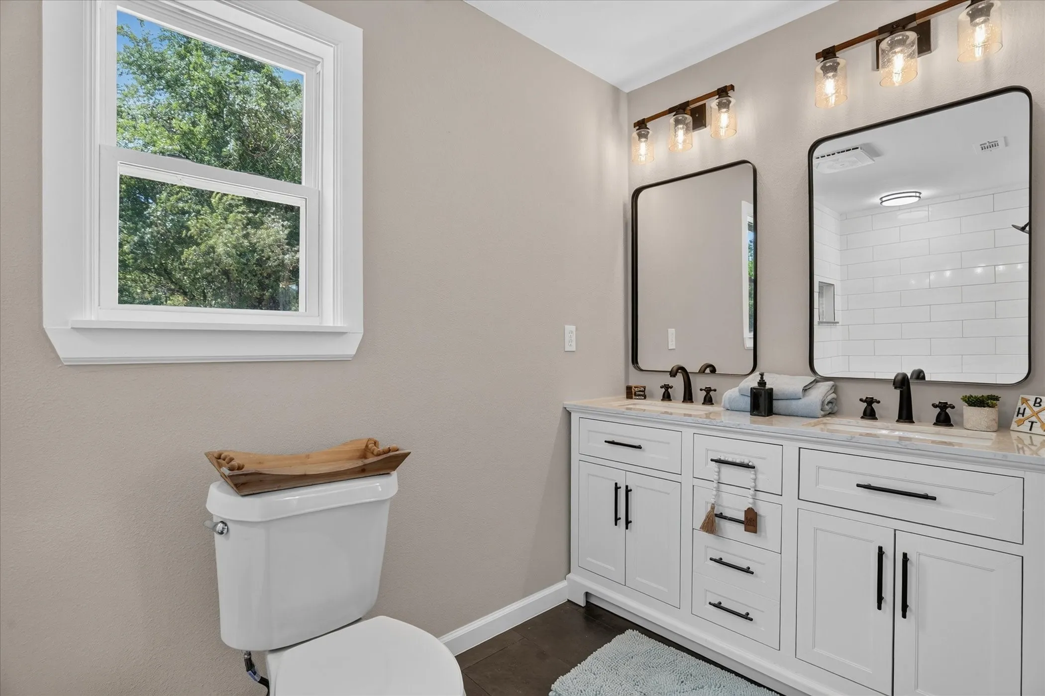 Dual vanity with white cabinetry and dark hardware, set against light-toned walls