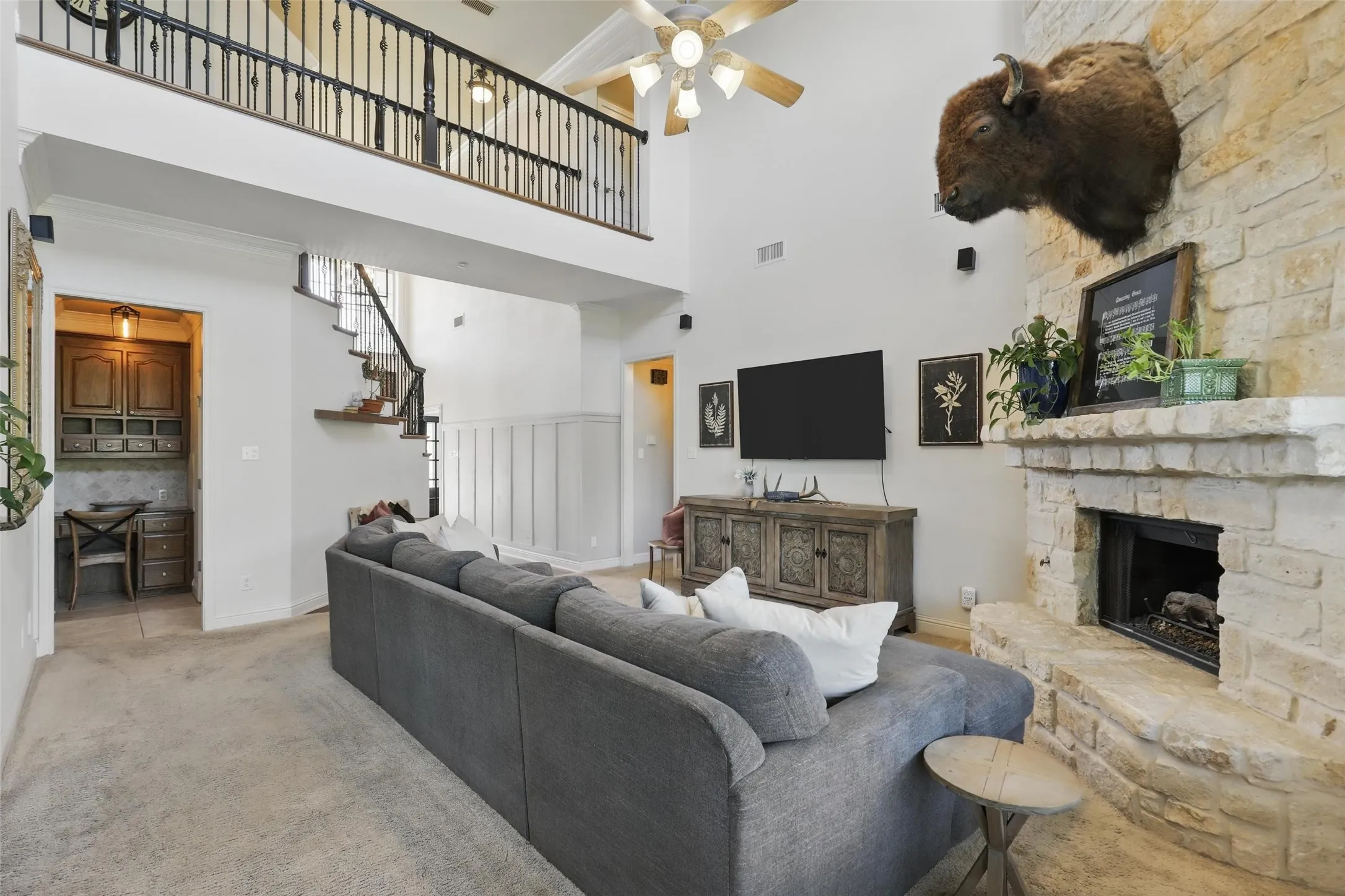 Spacious living area featuring a vaulted ceiling with a ceiling fan, a stone fireplace, and a built-in wood desk area
