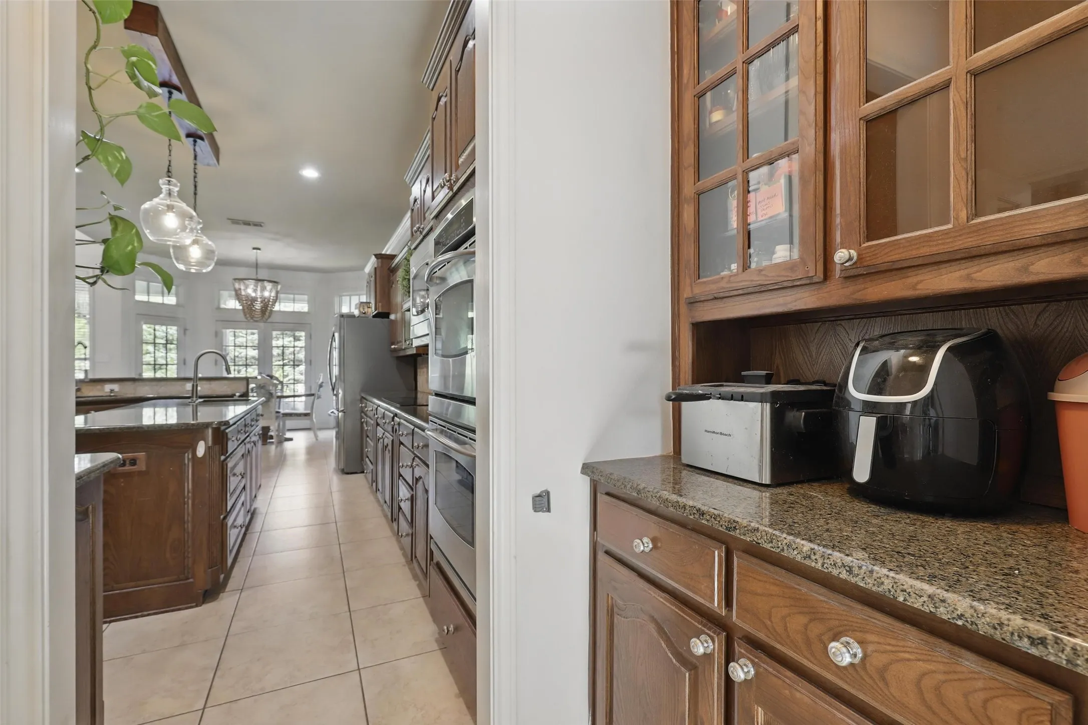 Kitchen featuring wood cabinetry, stainless steel appliances, a center island with sink, and tile flooring