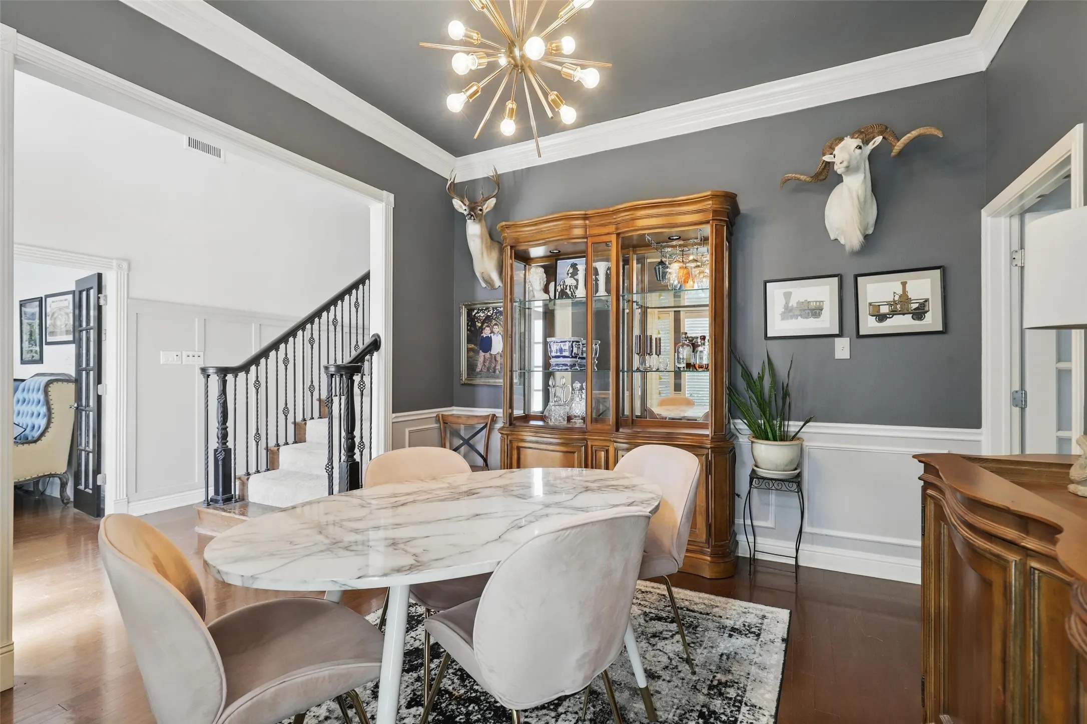 Formal dining space featuring dark wood-finish flooring, wainscoting, and crown molding