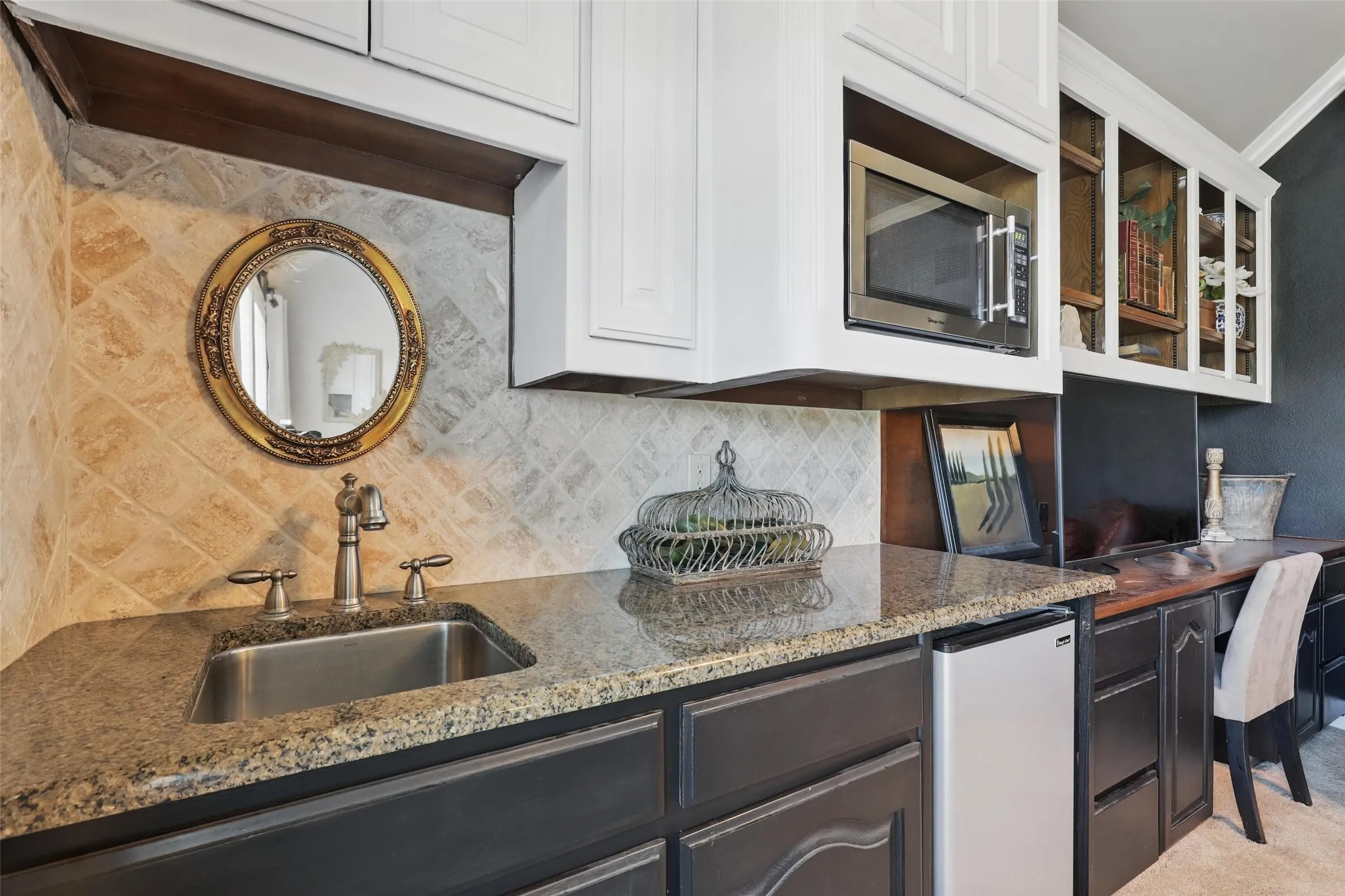 Wet bar featuring an undermount stainless steel sink with a brushed nickel faucet, granite countertops, and a tiled backsplash