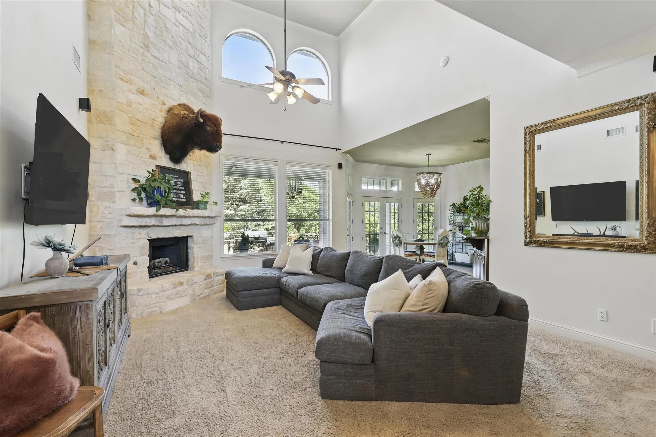 Living room featuring a stone-clad fireplace and hearth, vaulted ceilings, and arched windows