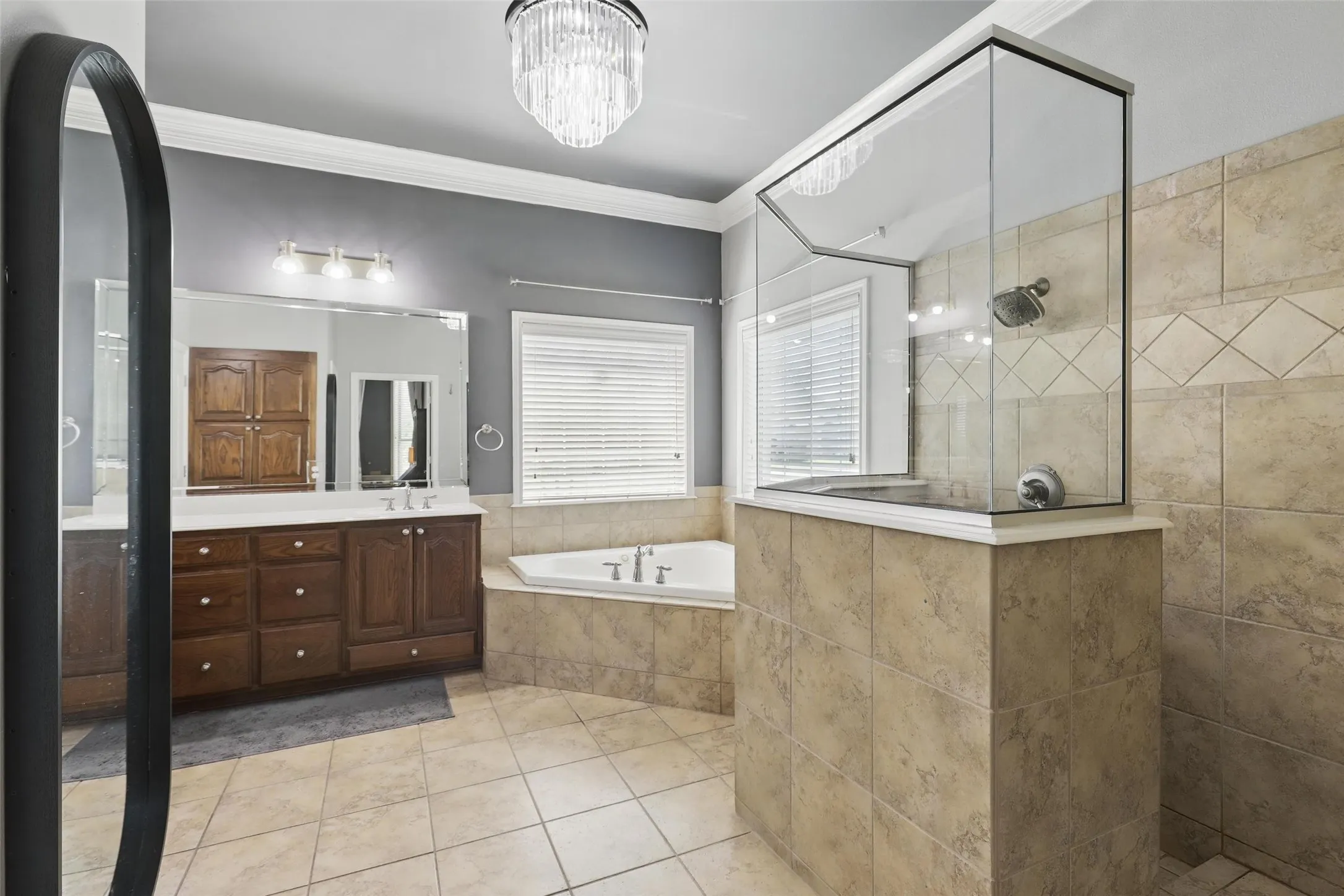 Spacious bathroom featuring a glass-enclosed shower, a corner built-in soaking tub, and a dual-sink vanity with wood cabinetry