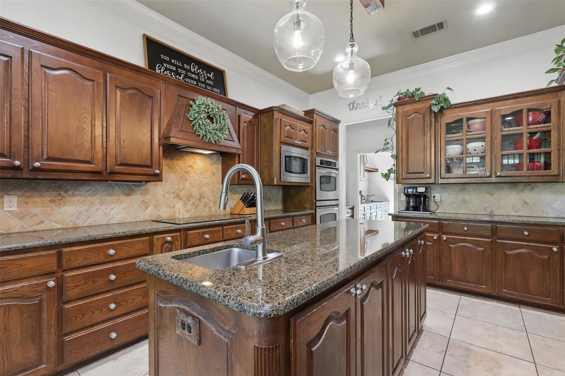 Spacious kitchen featuring extensive wood-finish cabinetry, granite countertops, and a stone tile backsplash