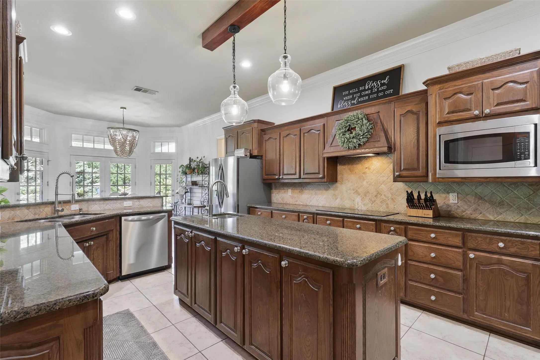 Spacious kitchen with a central island, rich wood cabinetry, stainless steel appliances, and granite countertops