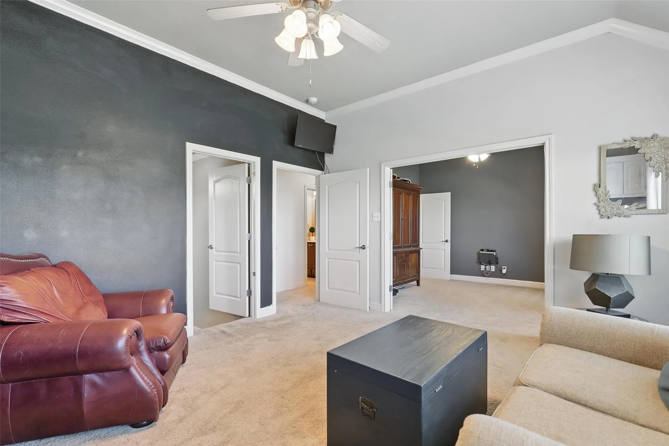 Carpeted room featuring a ceiling fan with integrated lighting, a vaulted ceiling, and multiple doorways