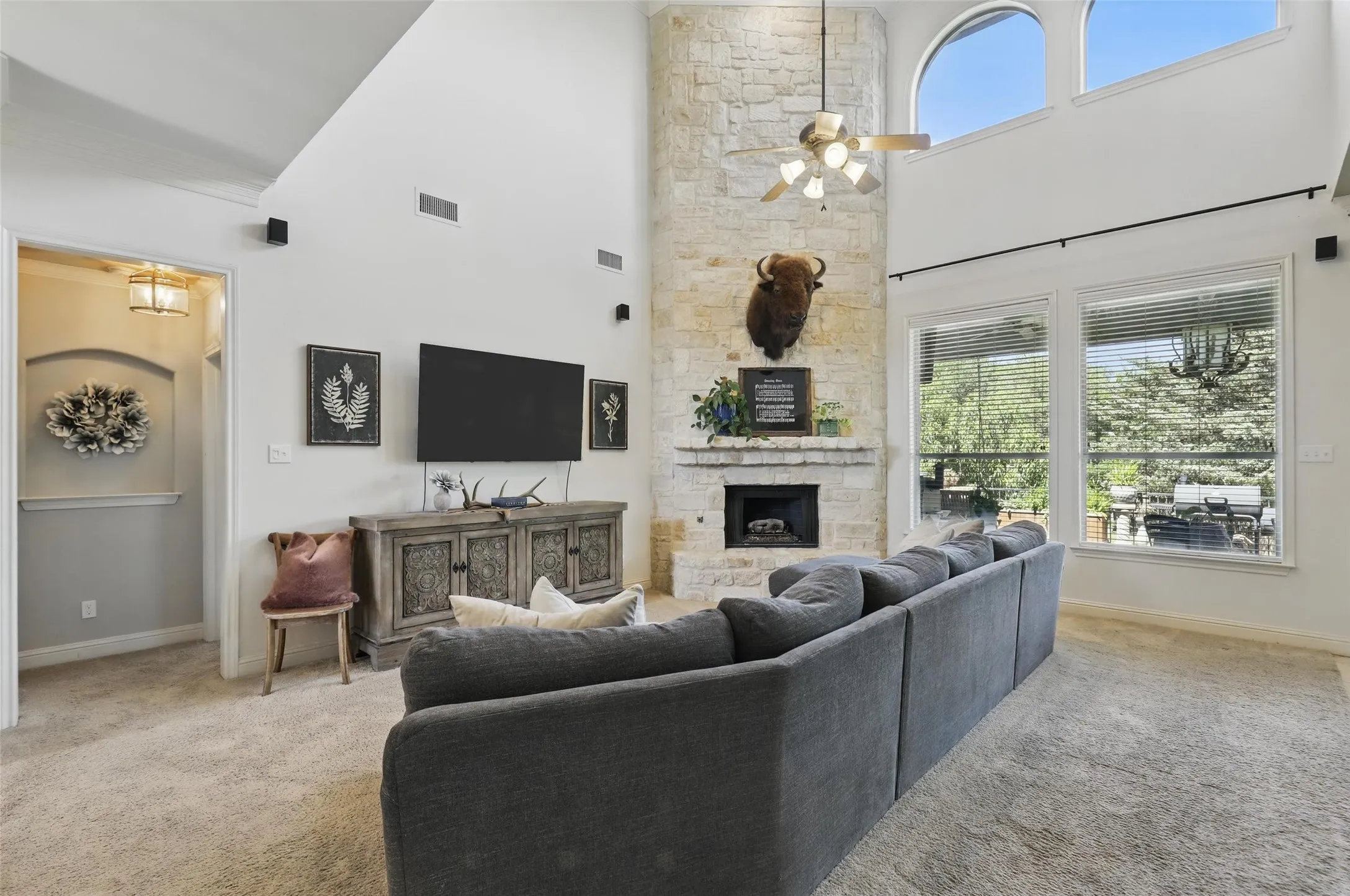 Living area featuring a floor-to-ceiling stone fireplace, soaring vaulted ceilings, and large windows with arched transoms
