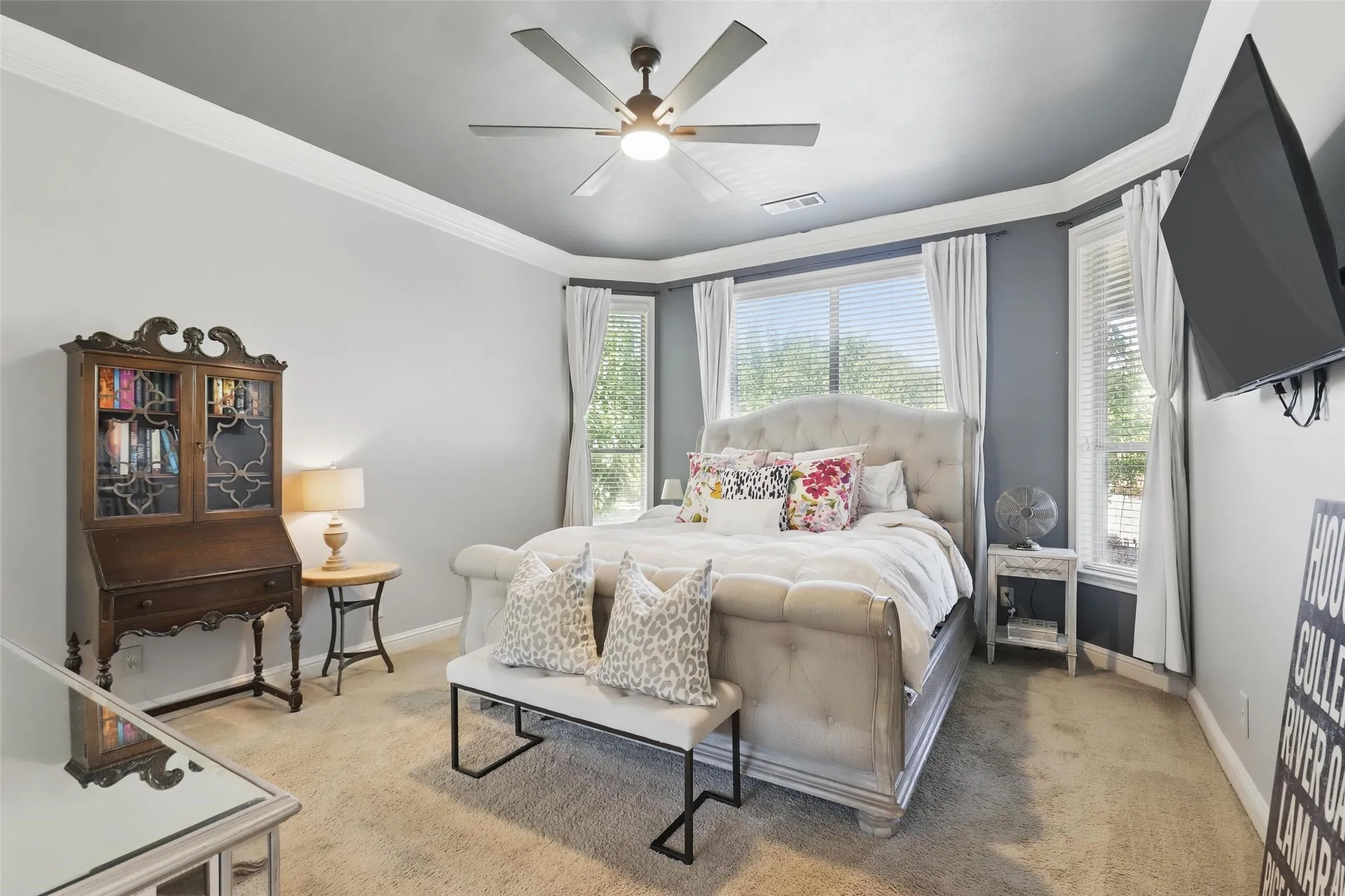 Carpeted bedroom featuring a ceiling fan with integrated lighting, crown molding, and a bay window