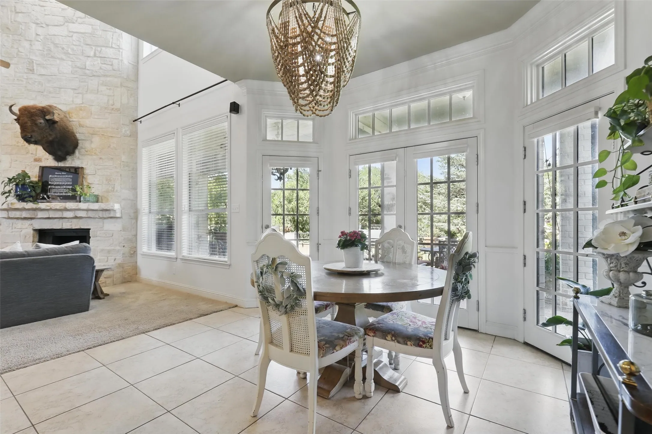 Dining area featuring a circular wood-finish table, tile flooring, and multiple exterior glass-paneled doors with transom windows