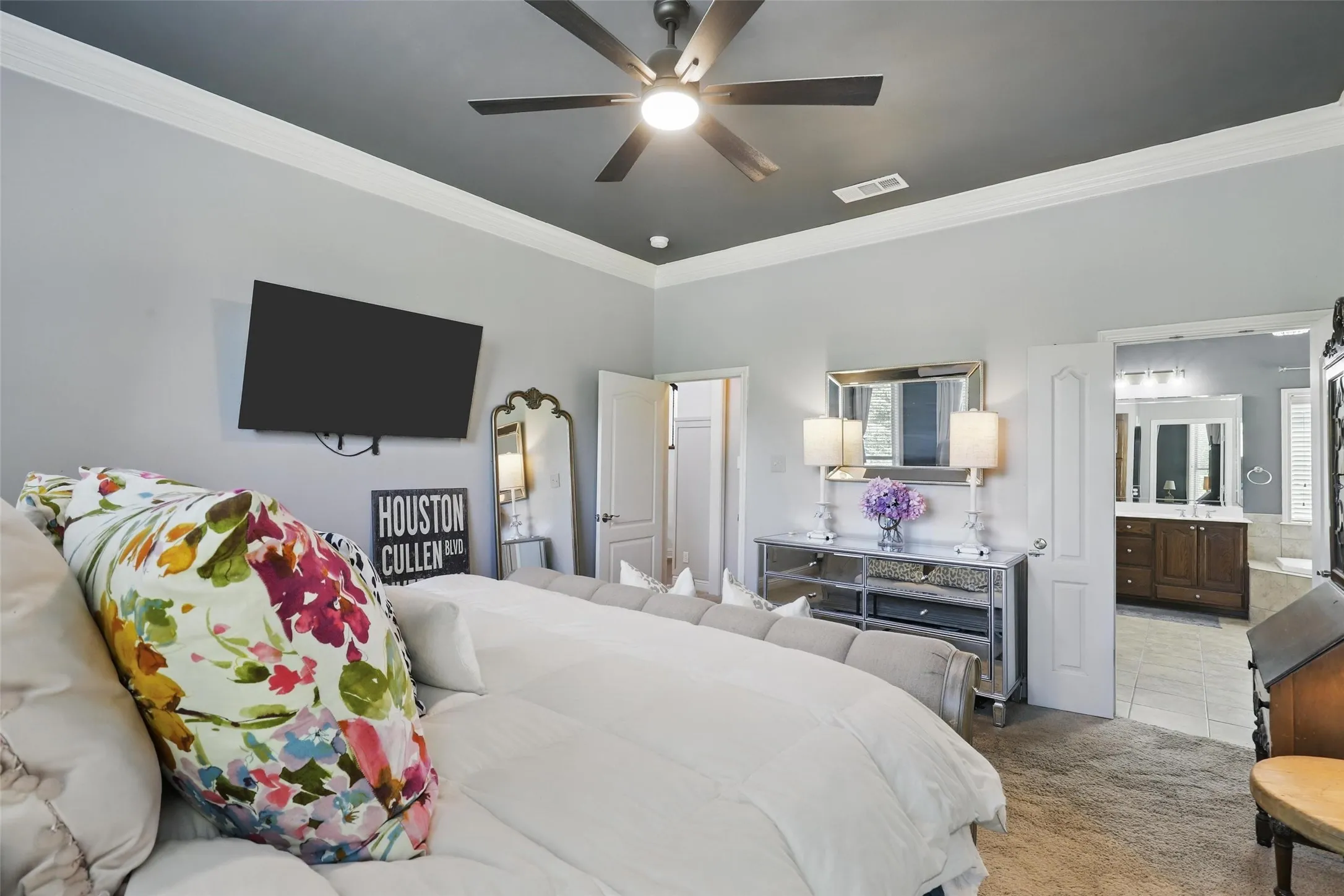 Carpeted room featuring a ceiling fan, wall-mounted television, and crown molding