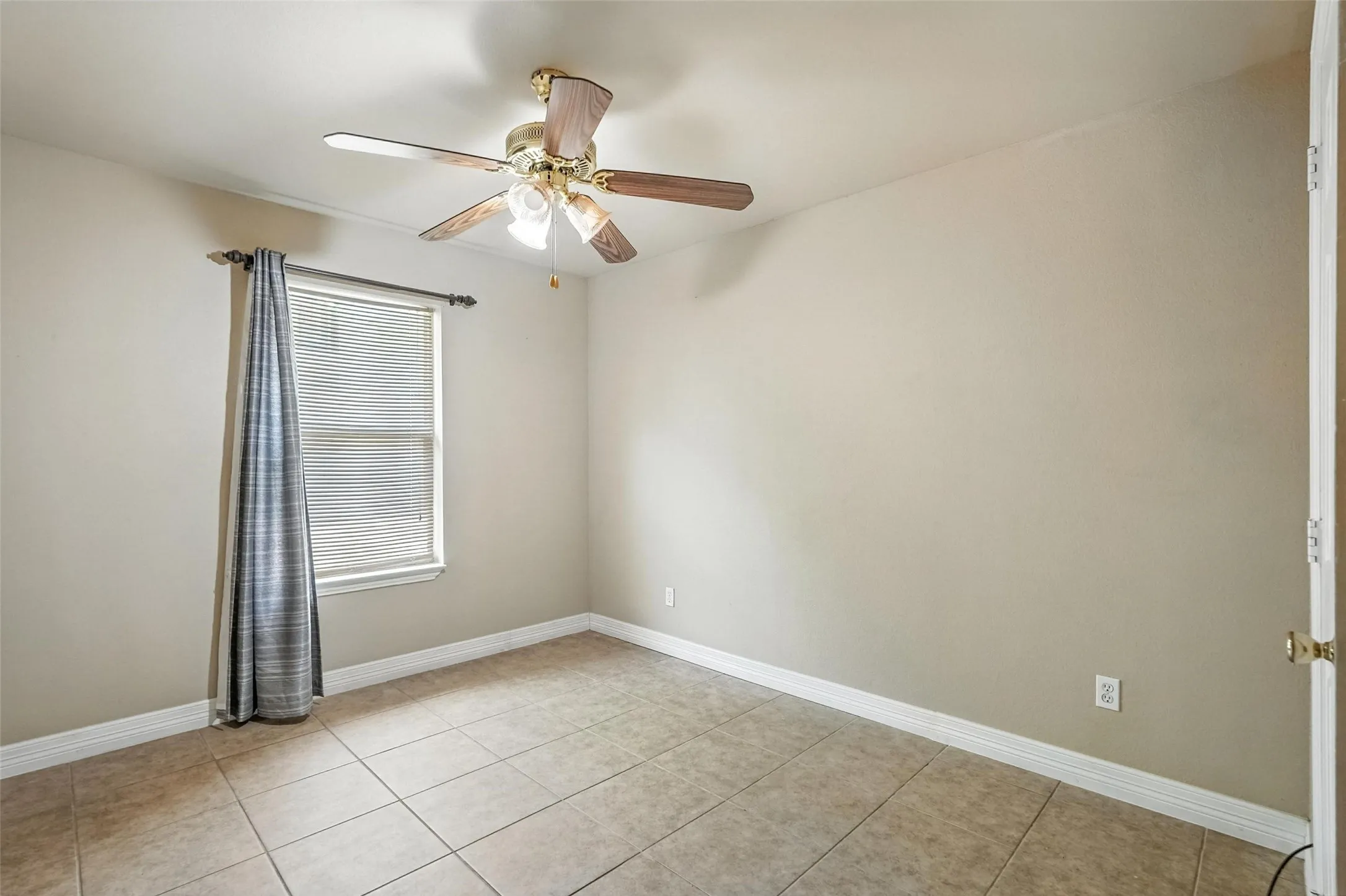 Spare room featuring light tile patterned floors and a ceiling fan