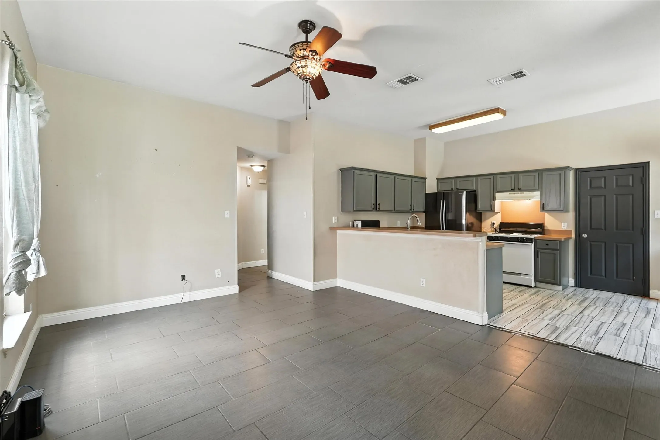 Unfurnished living room featuring a ceiling fan and wood finish floors