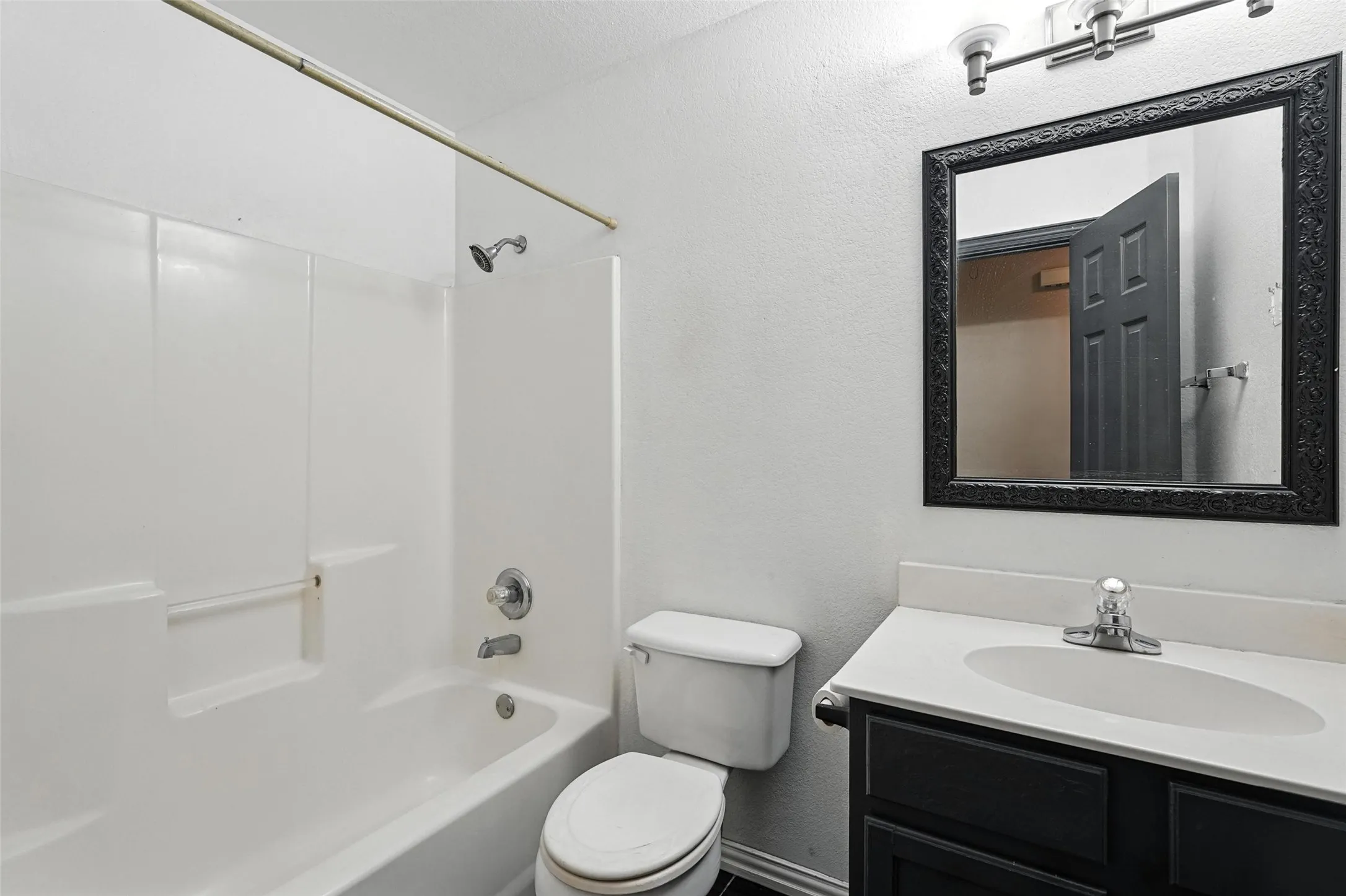 Bathroom with a textured wall, vanity, and shower / bath combination