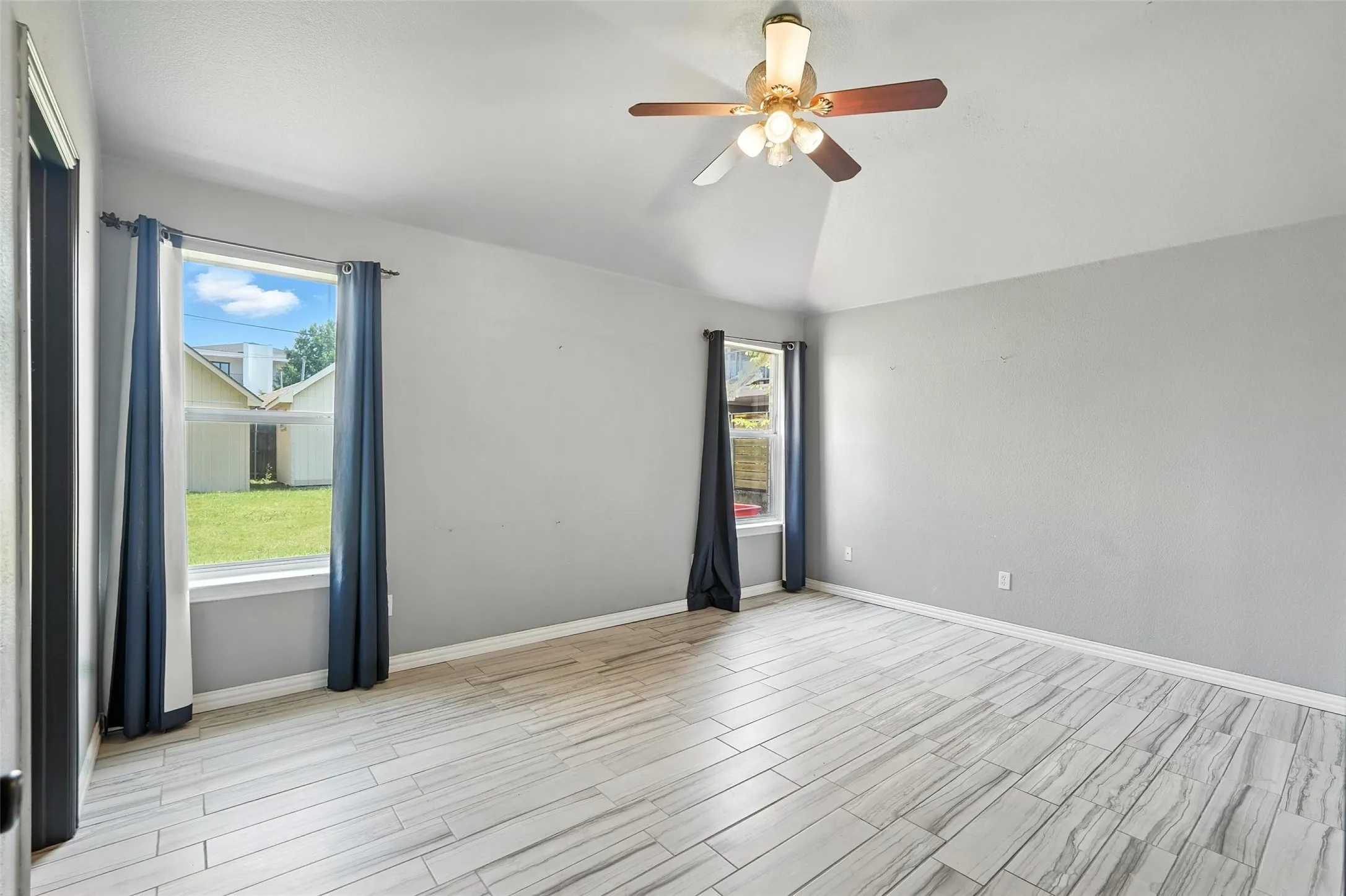 Spare room featuring wood tiled floors, lofted ceiling, and a ceiling fan