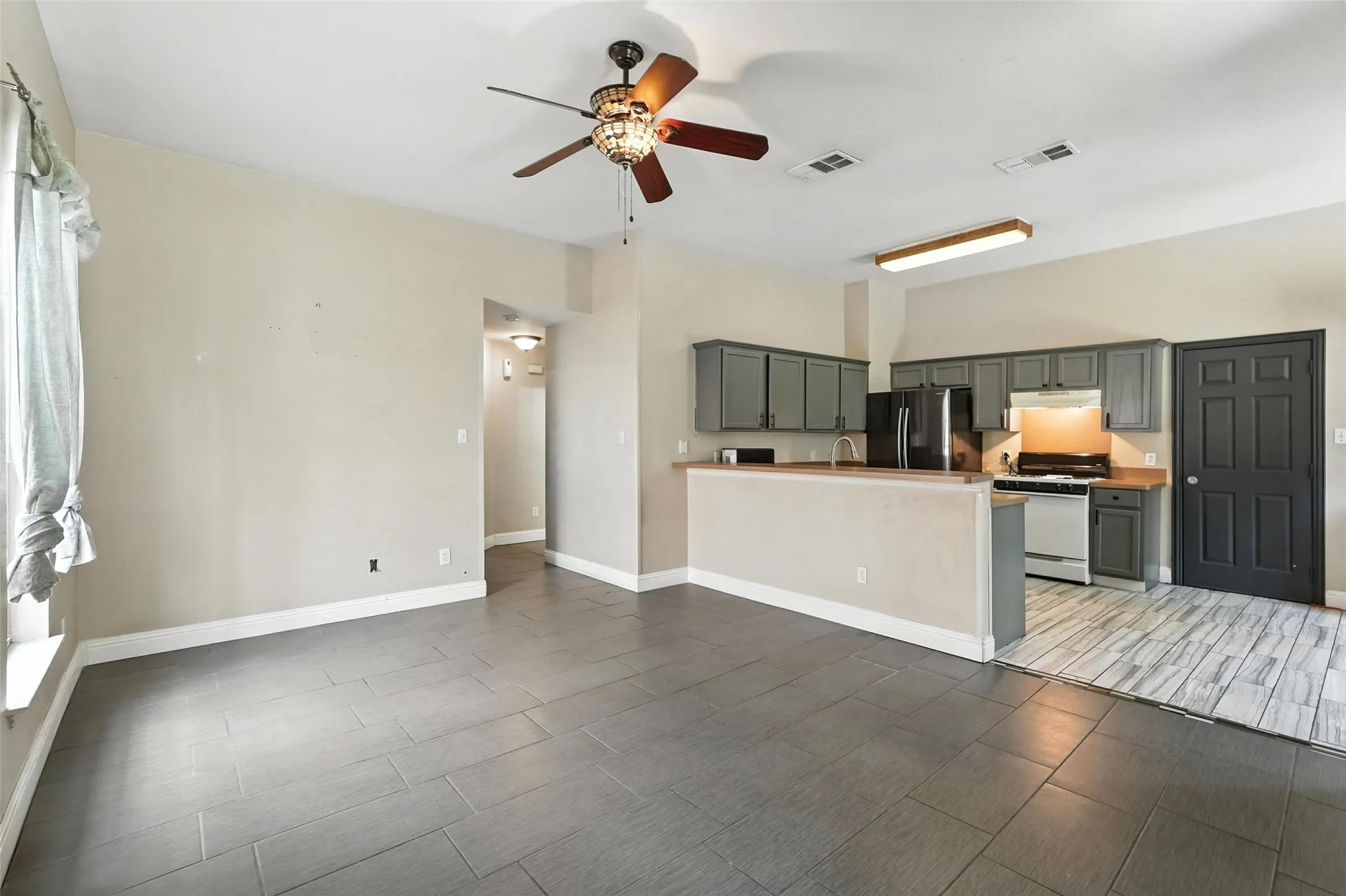Unfurnished living room featuring ceiling fan and wood tiled floors