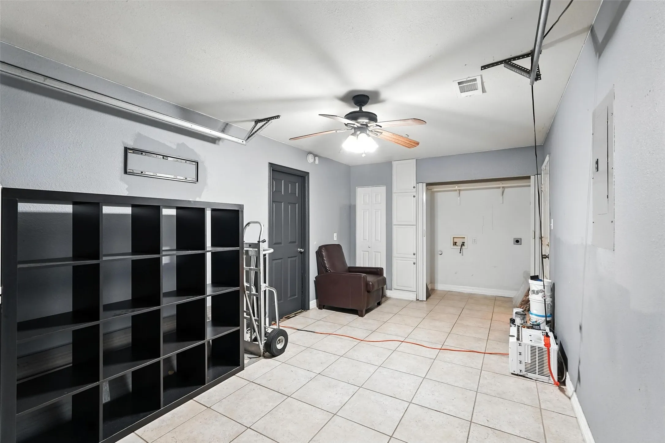 Entryway with light tile patterned floors, a ceiling fan, and electric panel