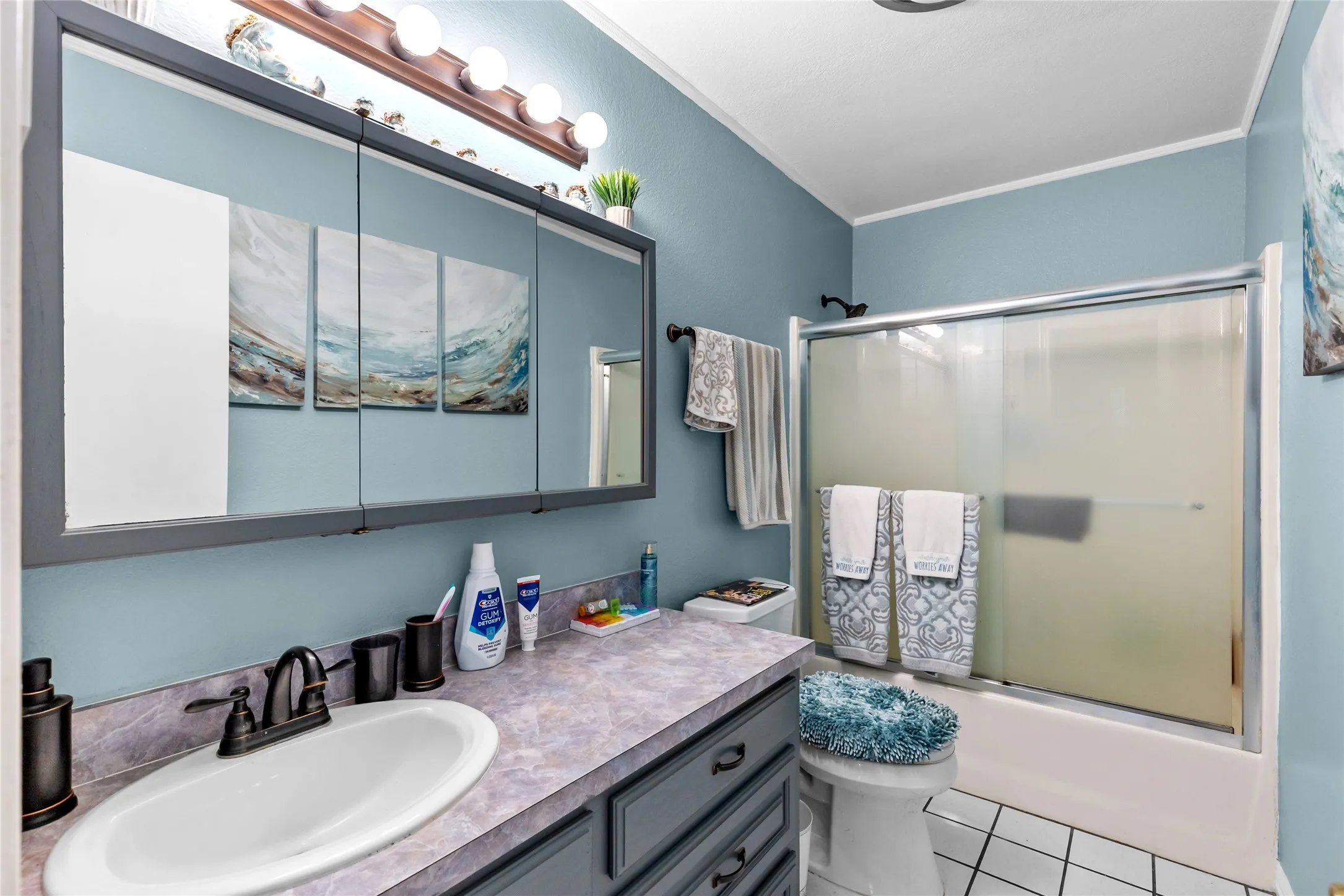 Vanity with oval sink, dark bronze faucet, and gray cabinetry