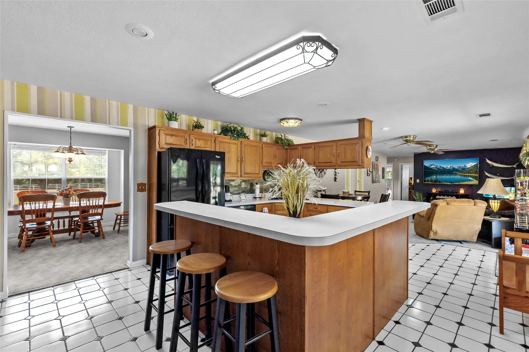 Kitchen featuring wood cabinetry, a breakfast bar, and black and white tile flooring