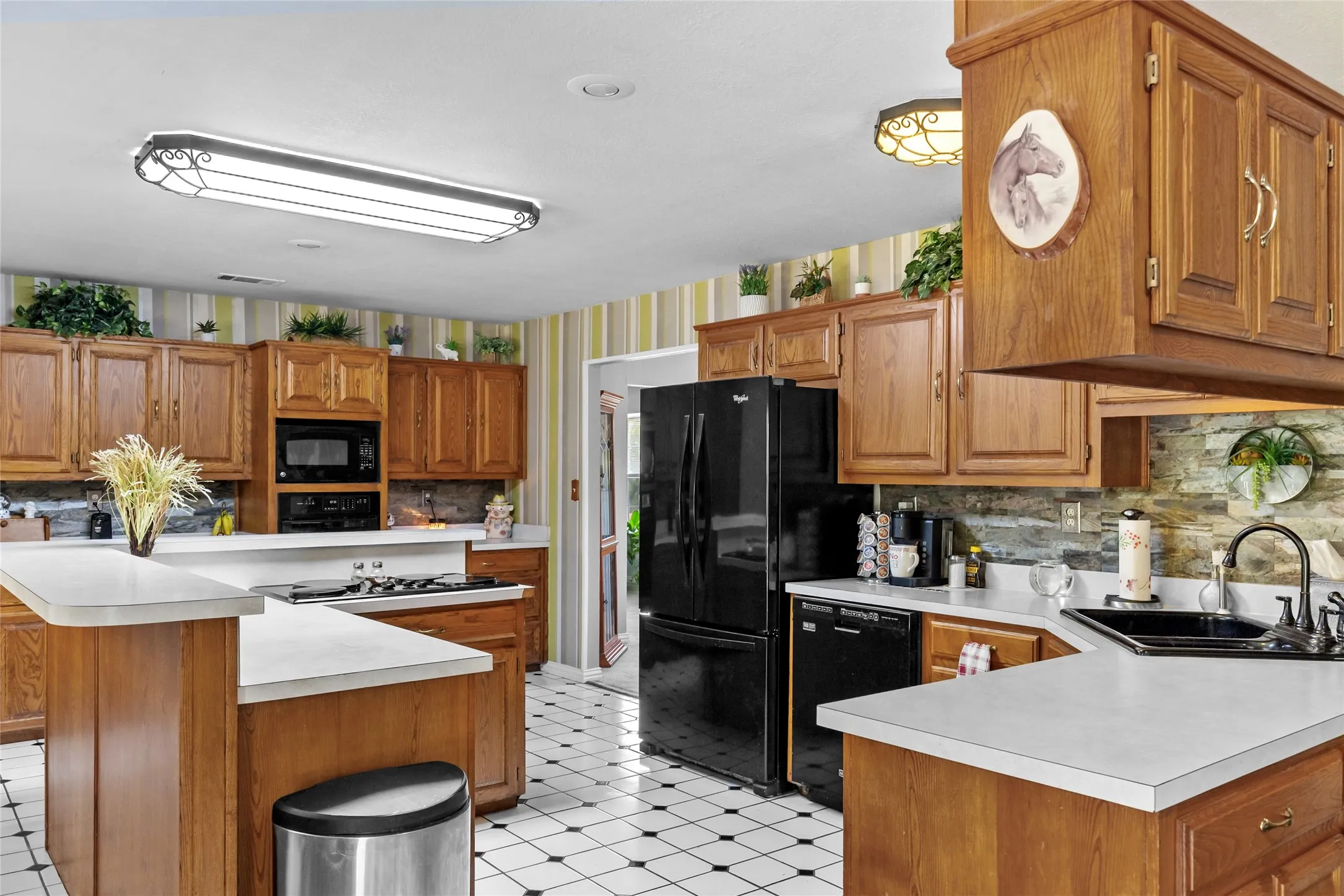 Spacious kitchen featuring warm wood cabinetry, white countertops, and black stainless steel appliances