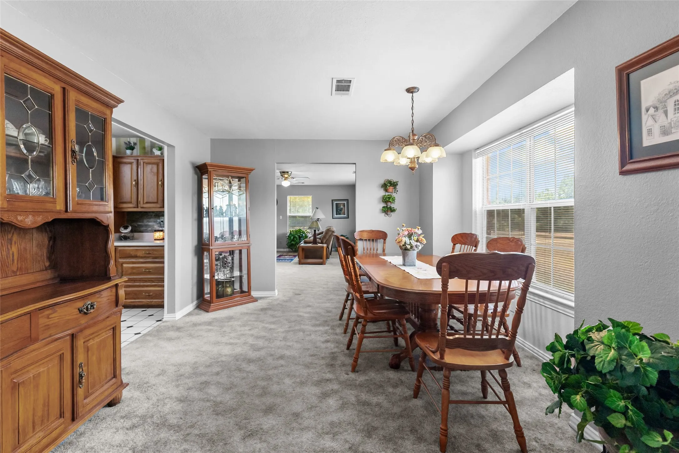 Carpeted dining area featuring a bay window, chandelier, and entryway to an additional room