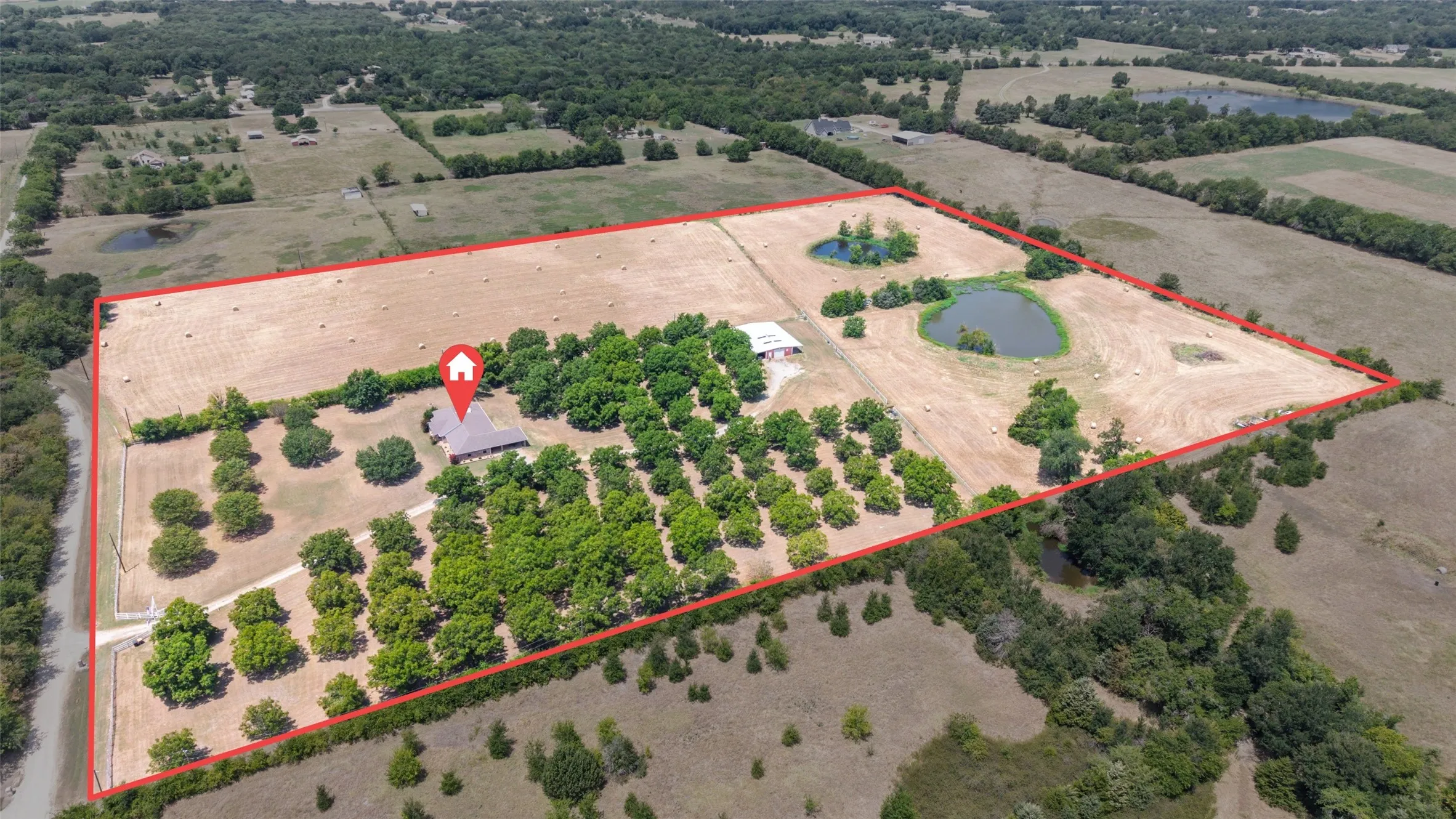 Expansive property featuring wooded areas, open fields, multiple ponds, and a single-story residence